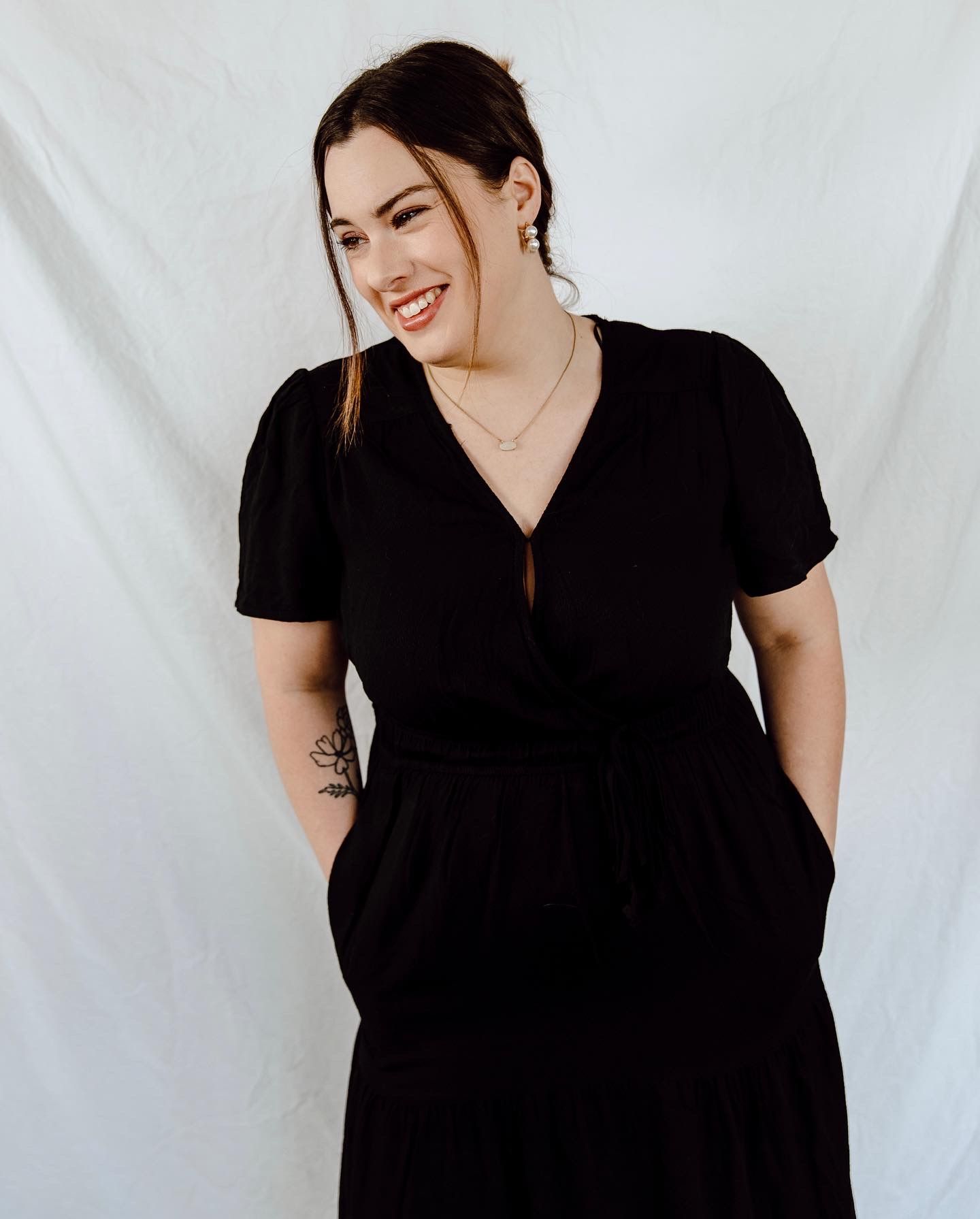 Studio portraits showing casual poses in black dress against white backdrop.