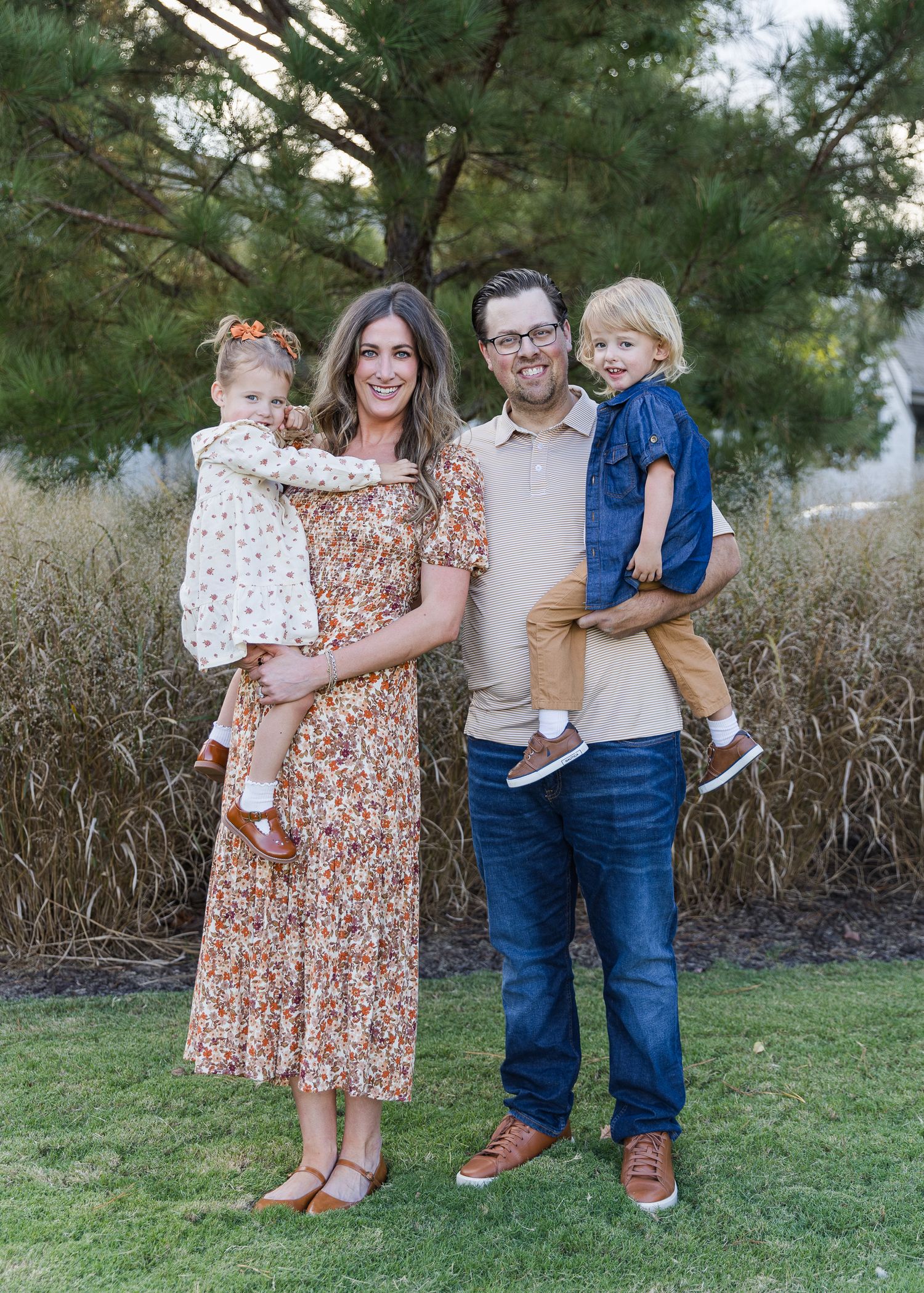 Family portrait session outdoors with coordinated outfits against natural backdrop.