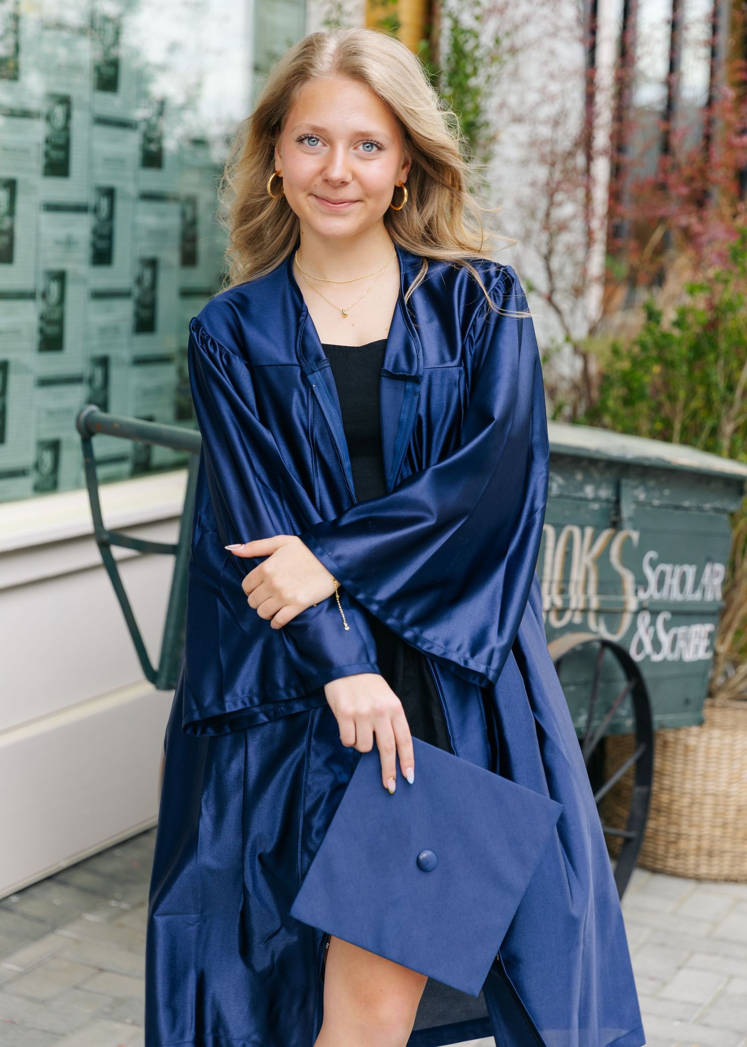 A person wearing a navy blue graduation gown and cap poses in various shots outdoors.