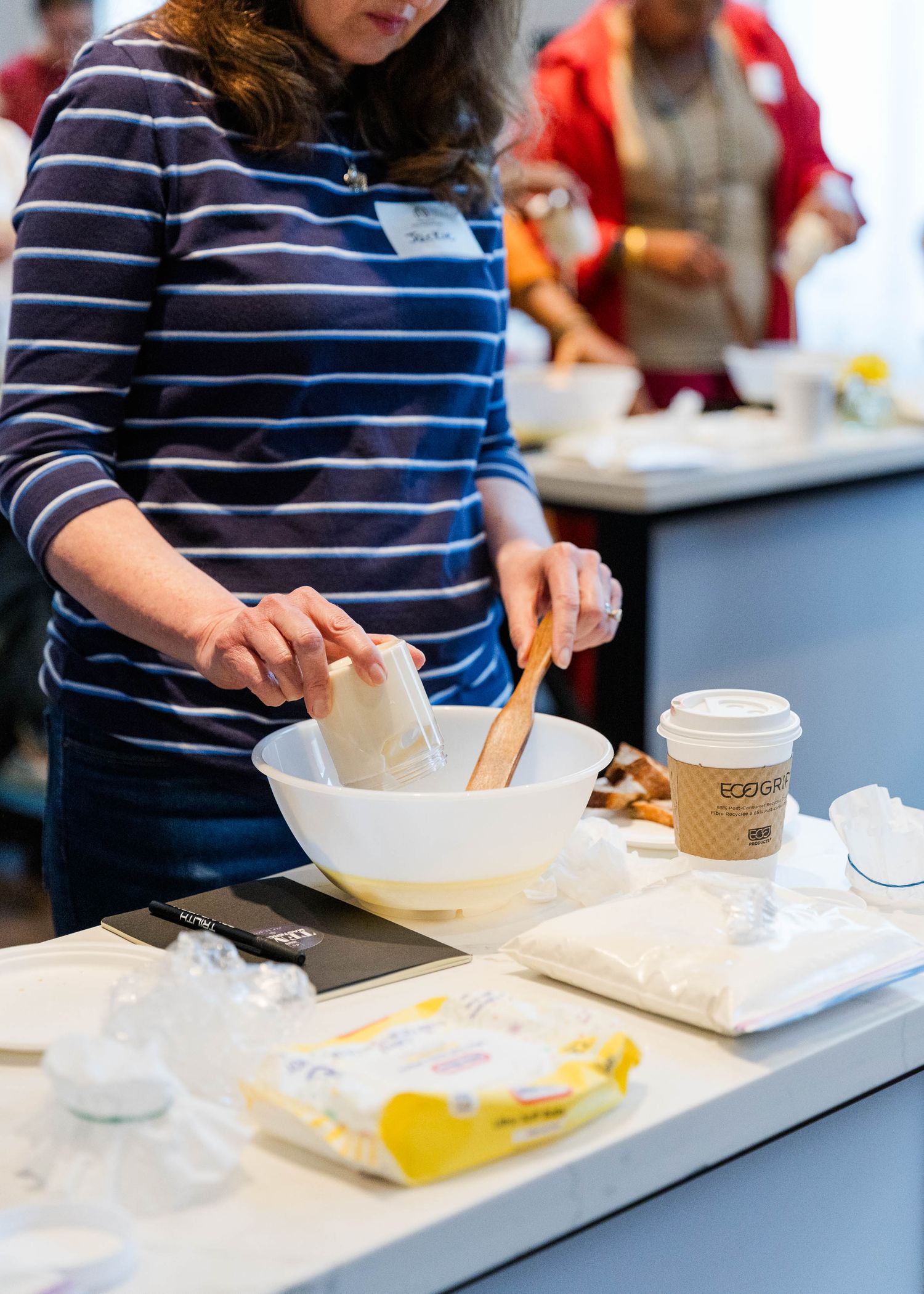 Someone in a striped shirt preparing food at a counter with various ingredients and containers.