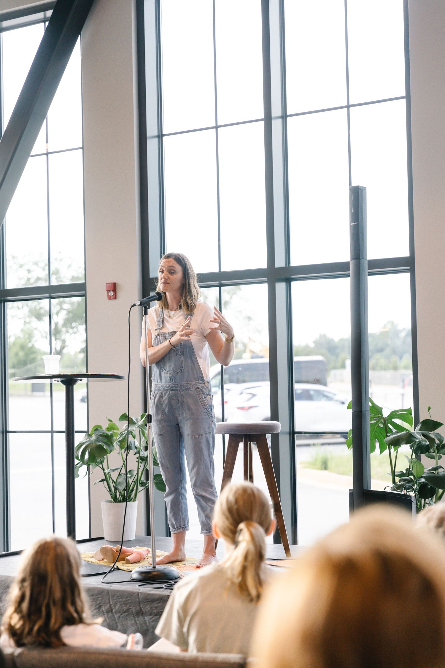 Bright modern event venue with floor-to-ceiling windows and people gathered for a presentation.