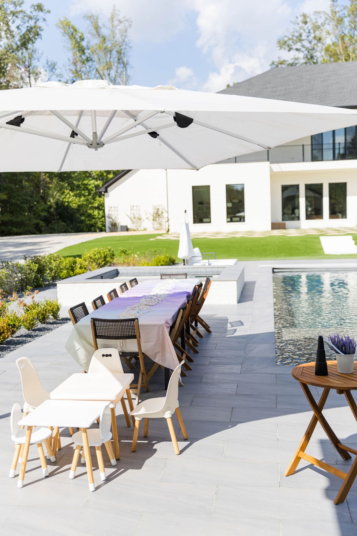 Elegant outdoor poolside setup with white umbrellas and wooden furniture.