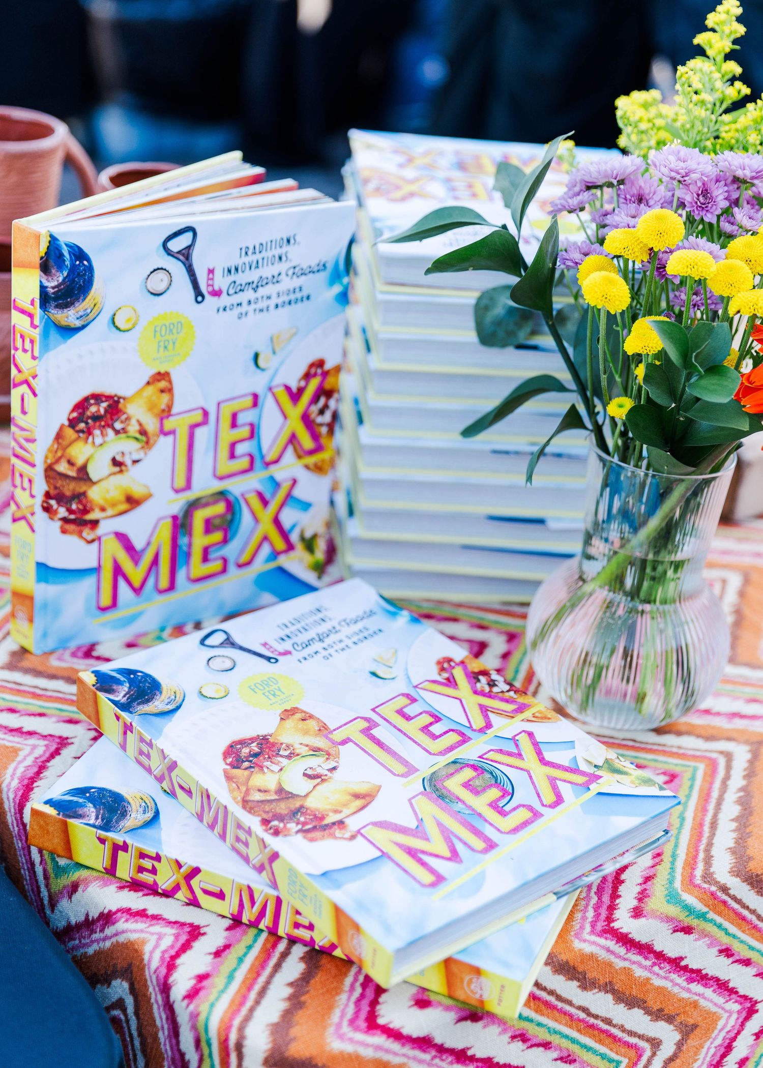 Colorful books and floral arrangements displayed on a table with Mexican-themed decorations.