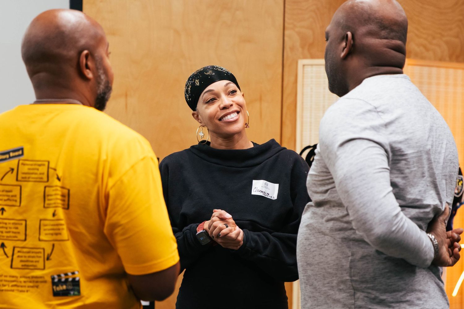 Group discussion in a casual setting with people wearing yellow and black clothing.