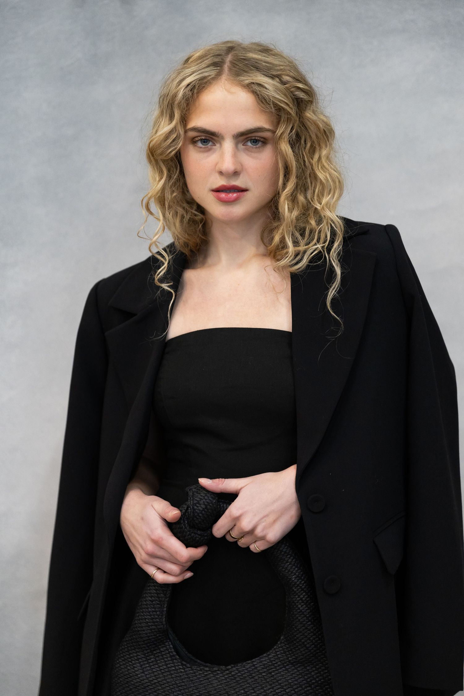Fashion portrait series showing a black blazer and top against a grey studio background.