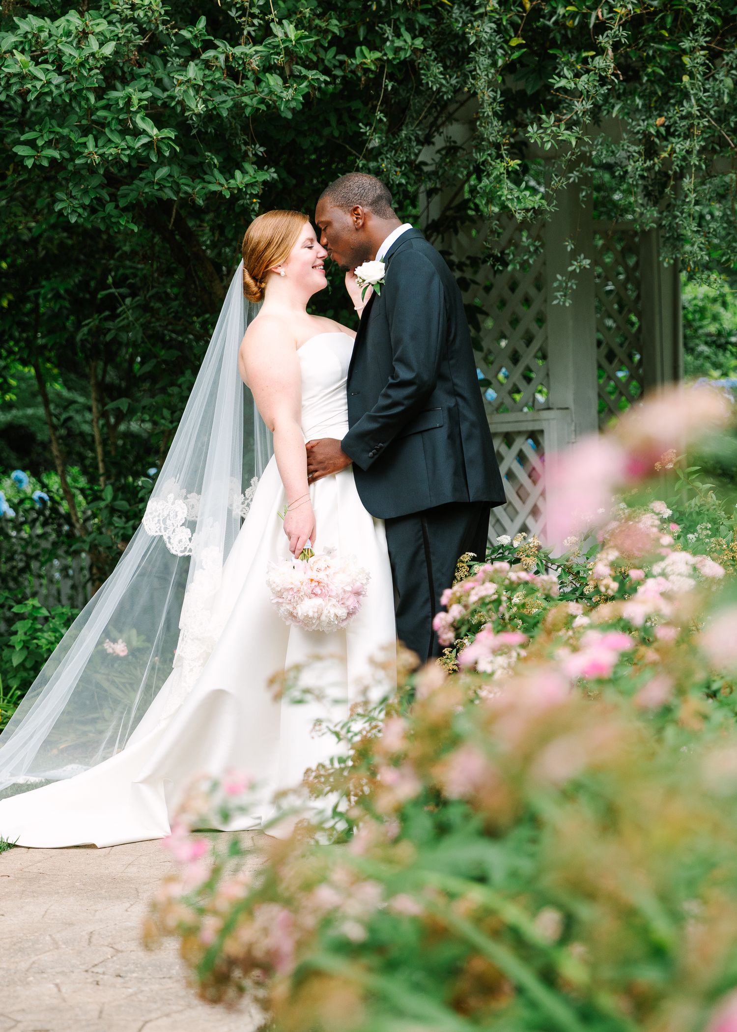 Wedding couple sharing intimate moments in a blooming garden setting.