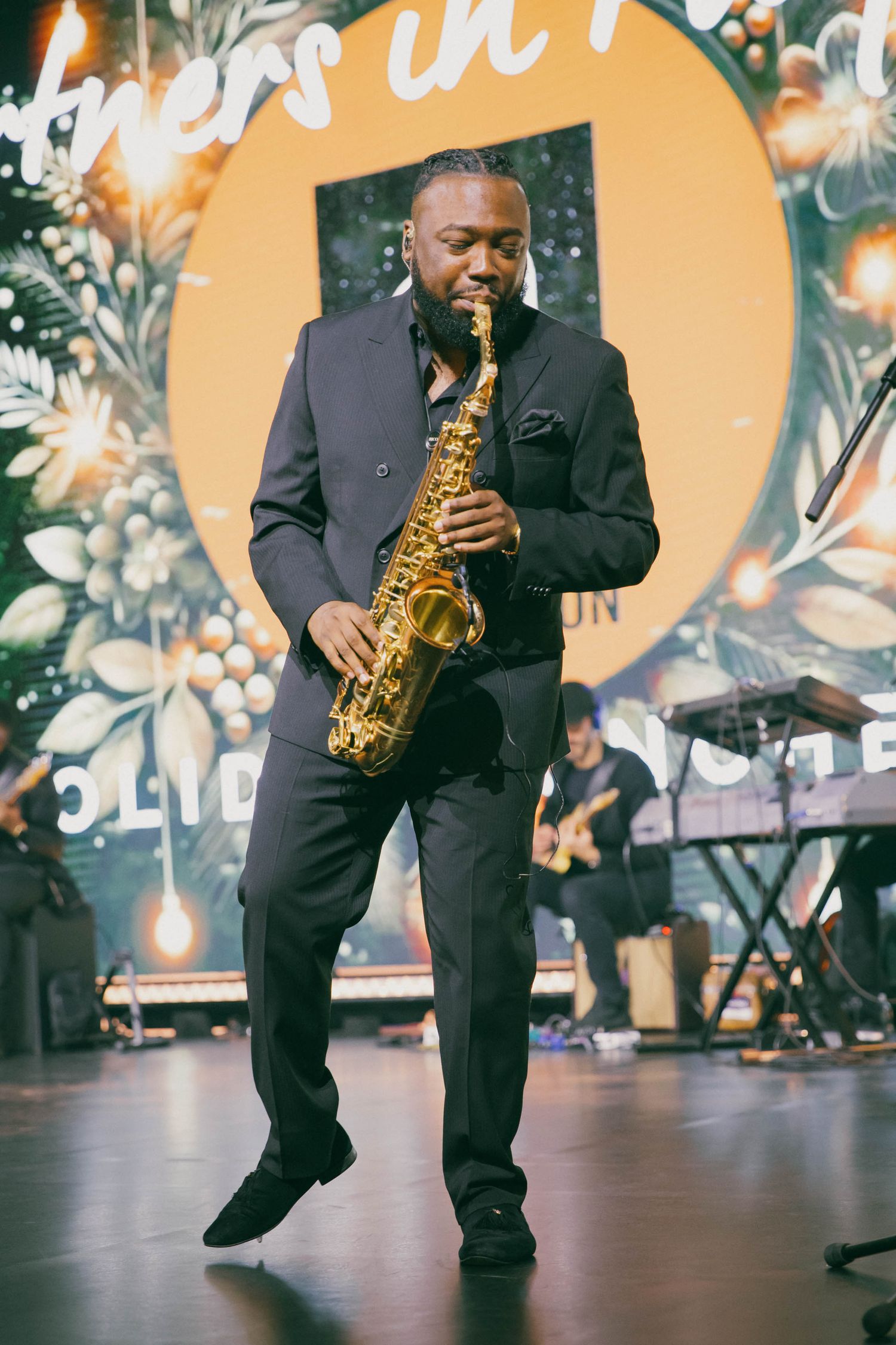 Musician performing with saxophone on stage during an event.