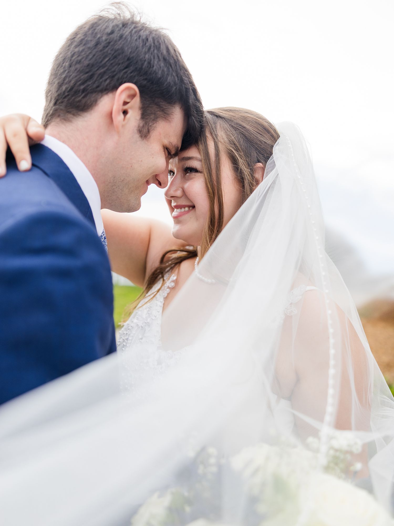 Romantic wedding portraits with flowing veil in soft natural light.