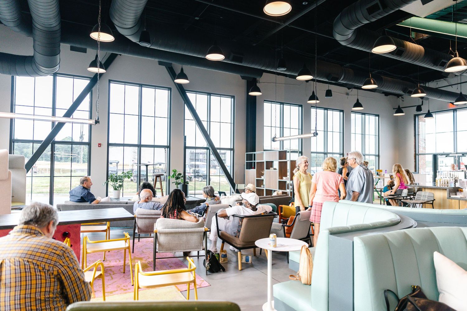 Contemporary office space with wooden floors and large windows featuring modern furniture and decor.