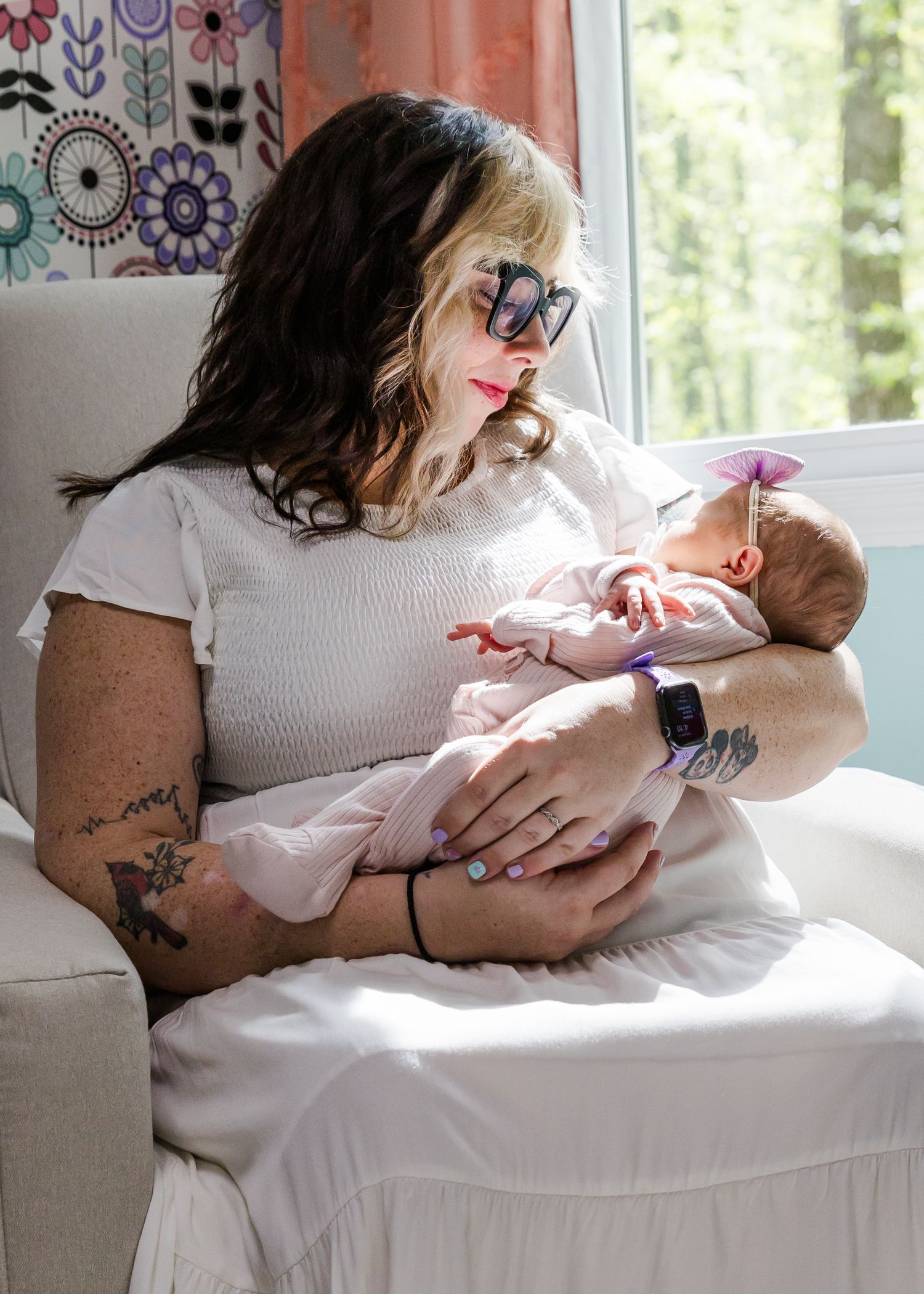 Parent and baby sharing tender moments on white bedding with colorful wall art in background.