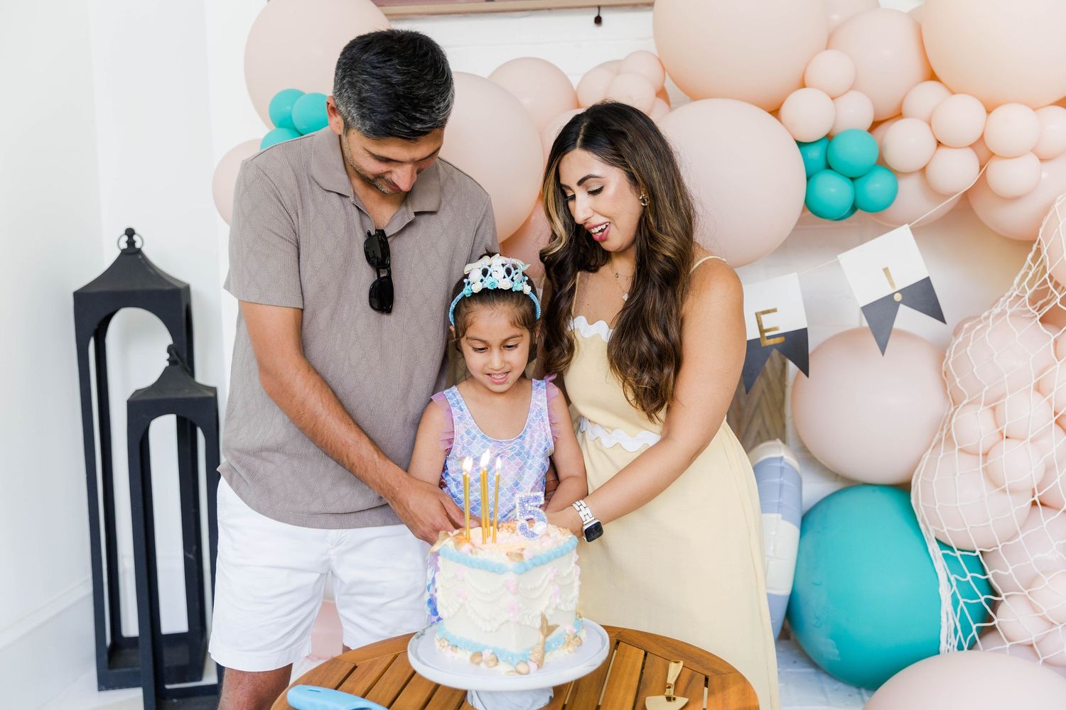 Birthday celebration setup with pink and turquoise balloon decorations and family gathering.