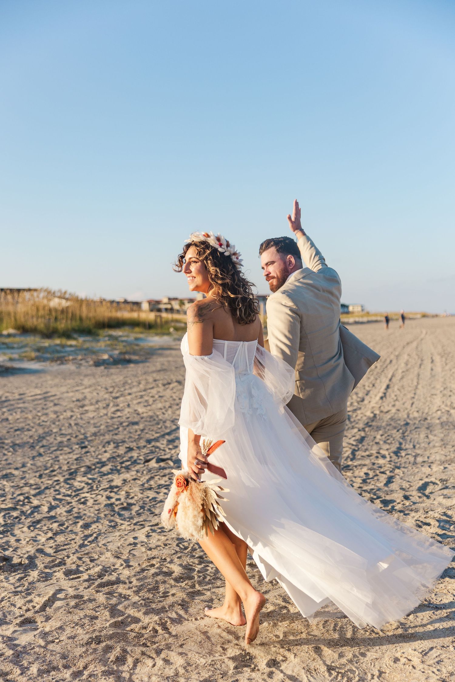 Playful beach wedding photos with couple running and dancing on sandy shore.