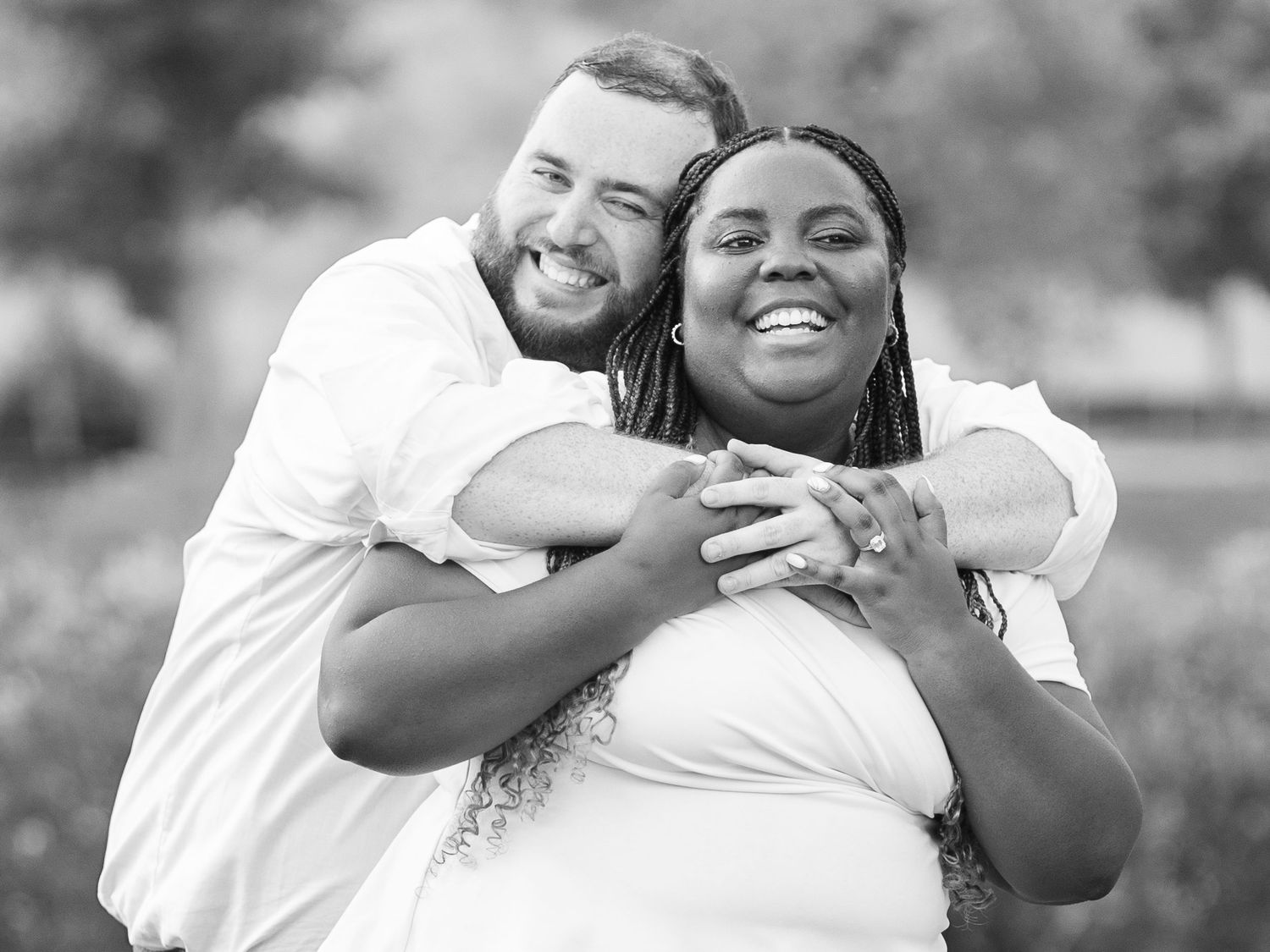 Couple shares joyful embrace during black and white outdoor photoshoot.