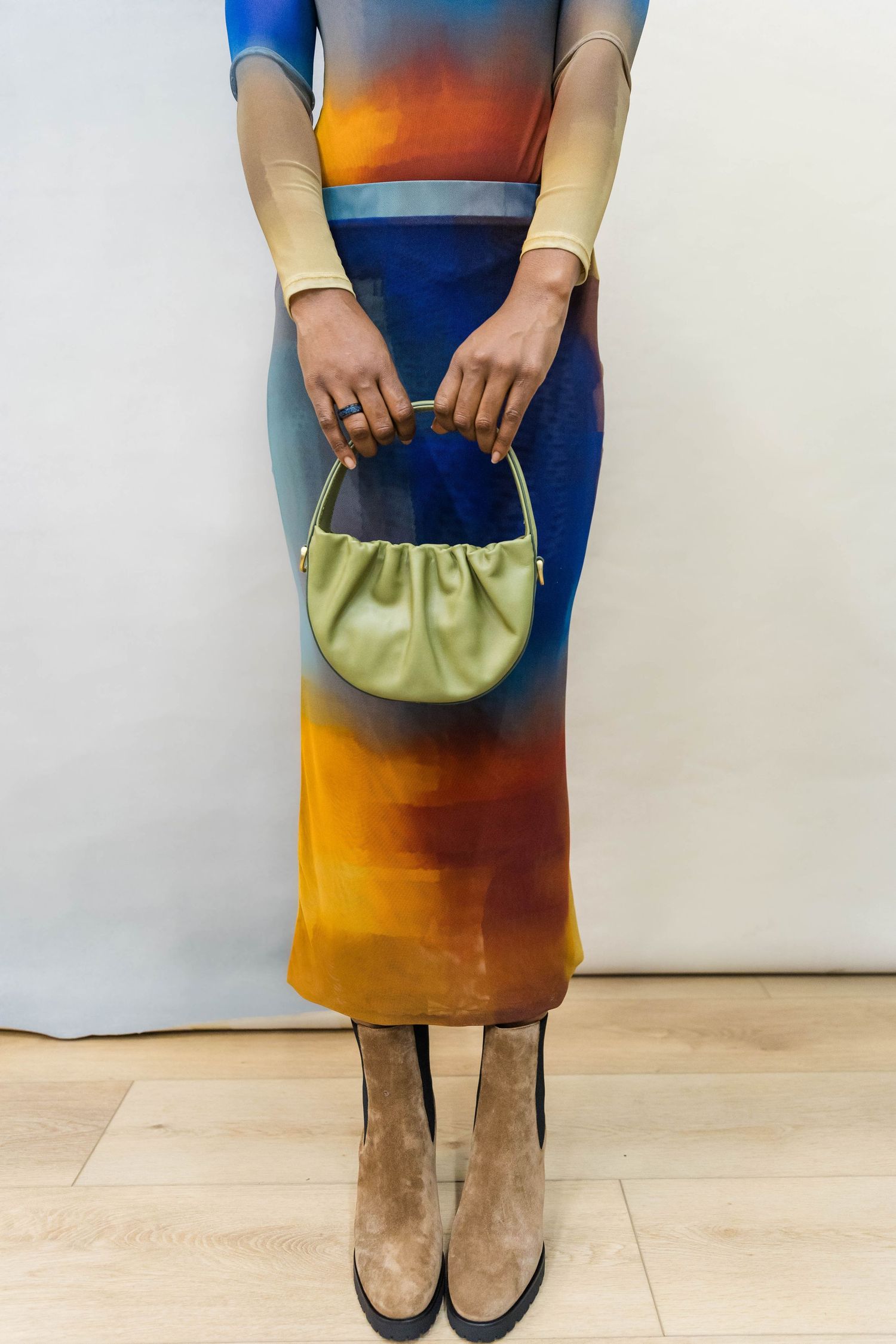 Gradient blue and orange dress paired with a mint green handbag and neutral shoes.