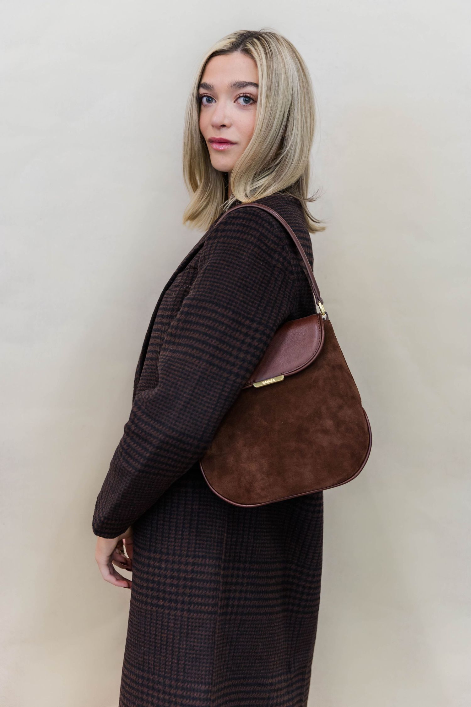 Brown plaid coat paired with suede shoulder bag in minimalist winter fashion.