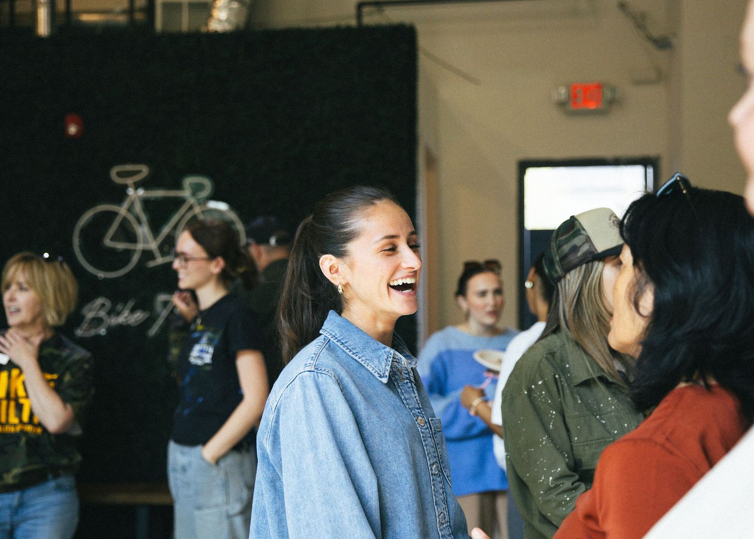 People gather in a dimly lit indoor space for what appears to be an event or meeting.