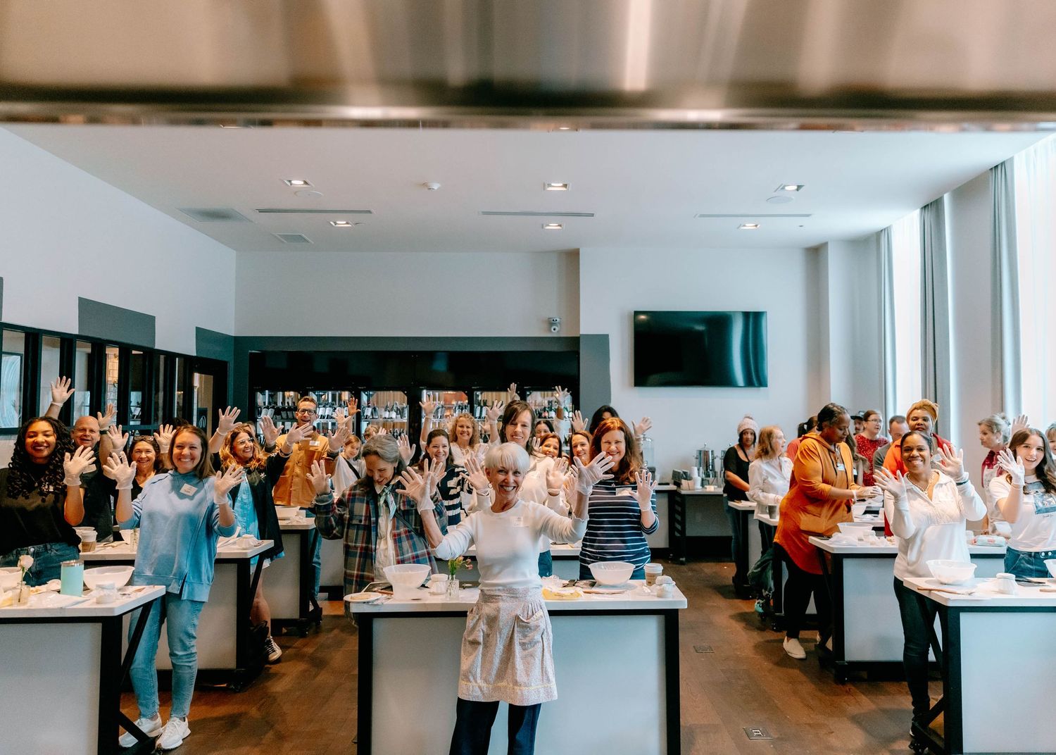Wide shot of a large group gathered in a modern kitchen space for a culinary event.