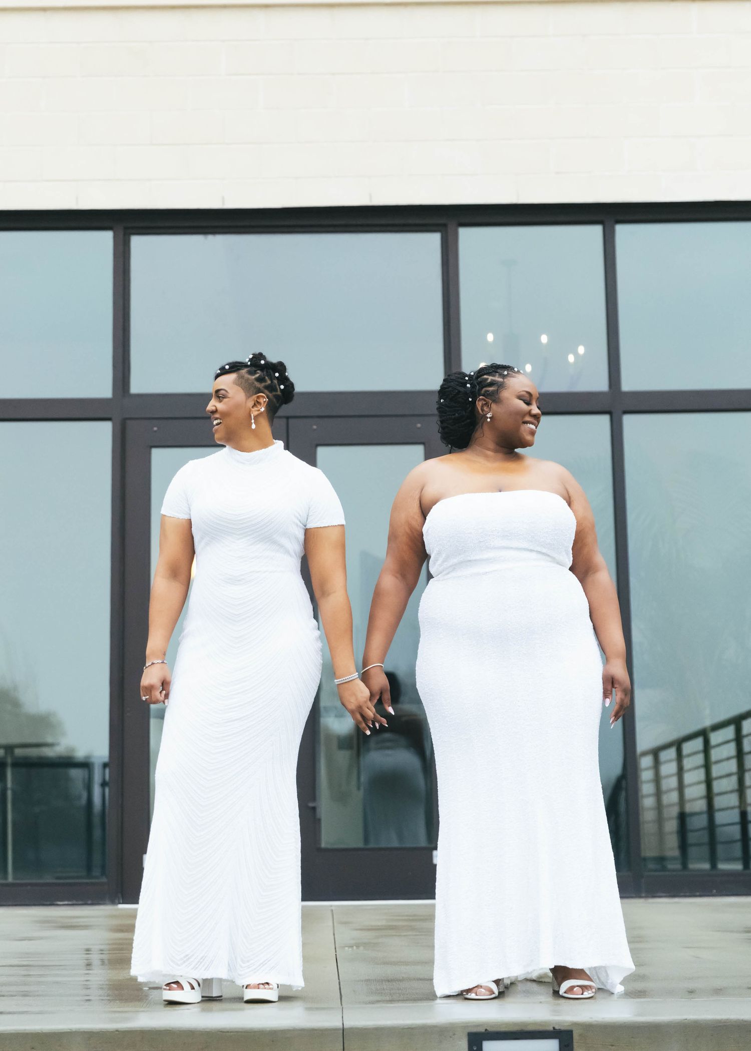 Row of people in white dresses standing against a modern building exterior.