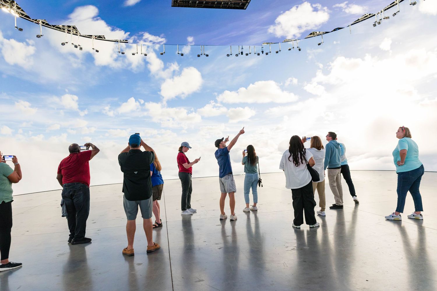 A group of visitors admiring a scenic overlook from a viewing platform on a bright sunny day.
