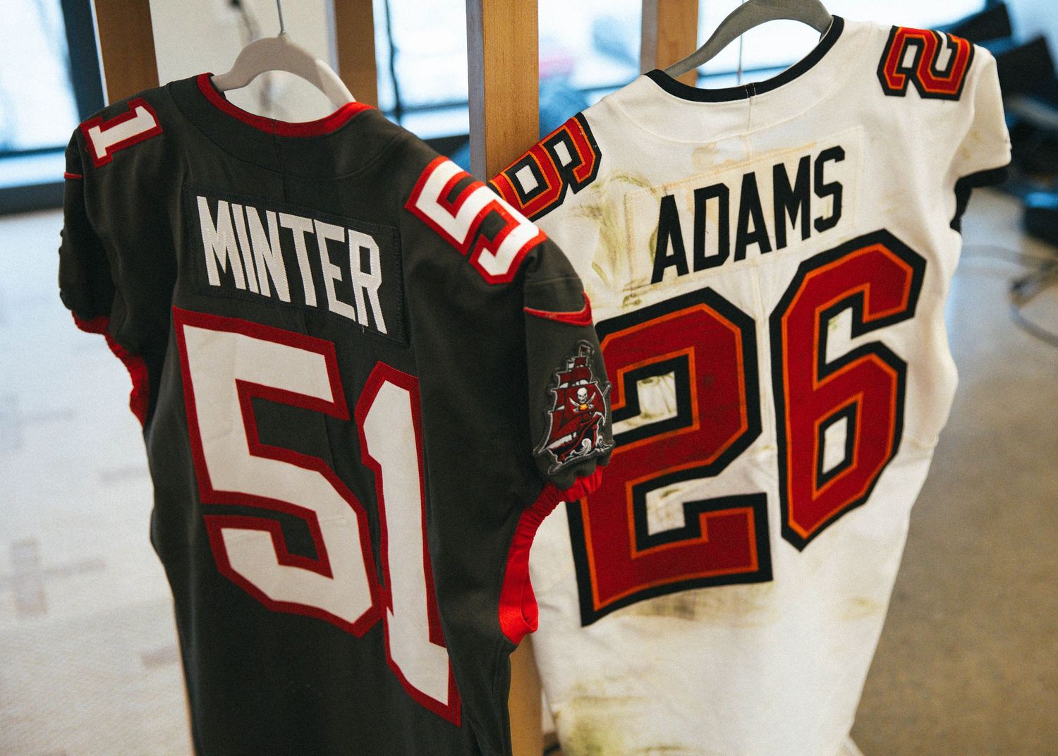 Display of sports jerseys including numbers 26 and 52 hanging on a wall.