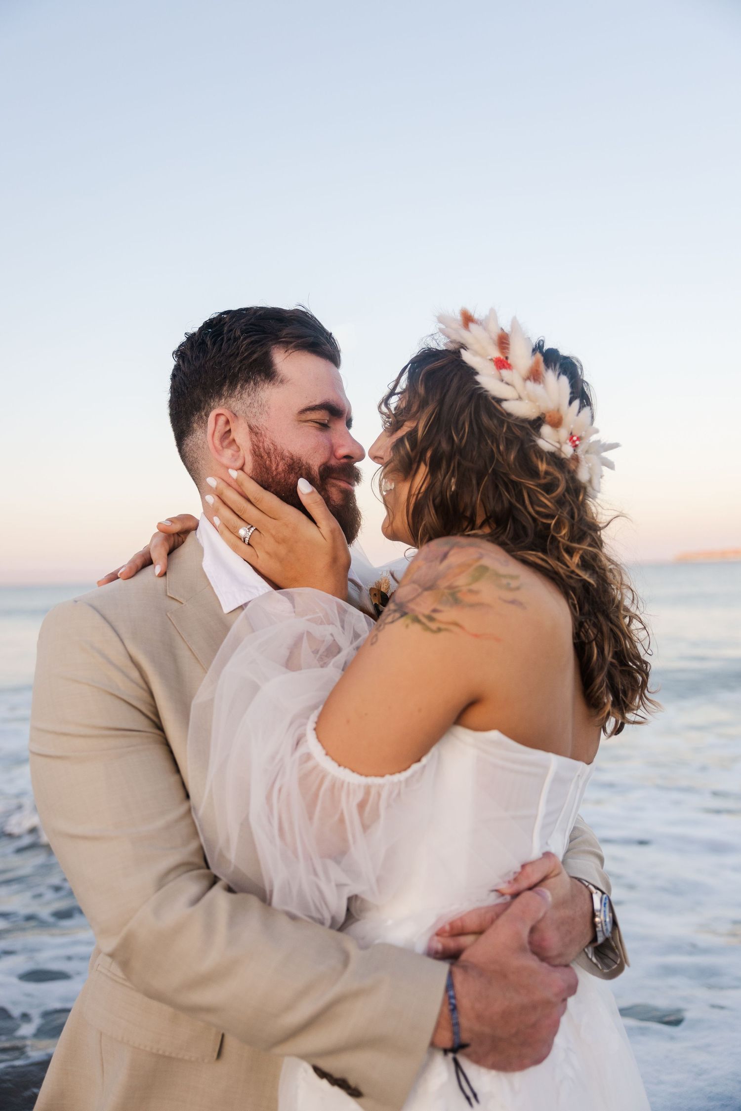 A tender wedding moment captured at the beach during golden hour.