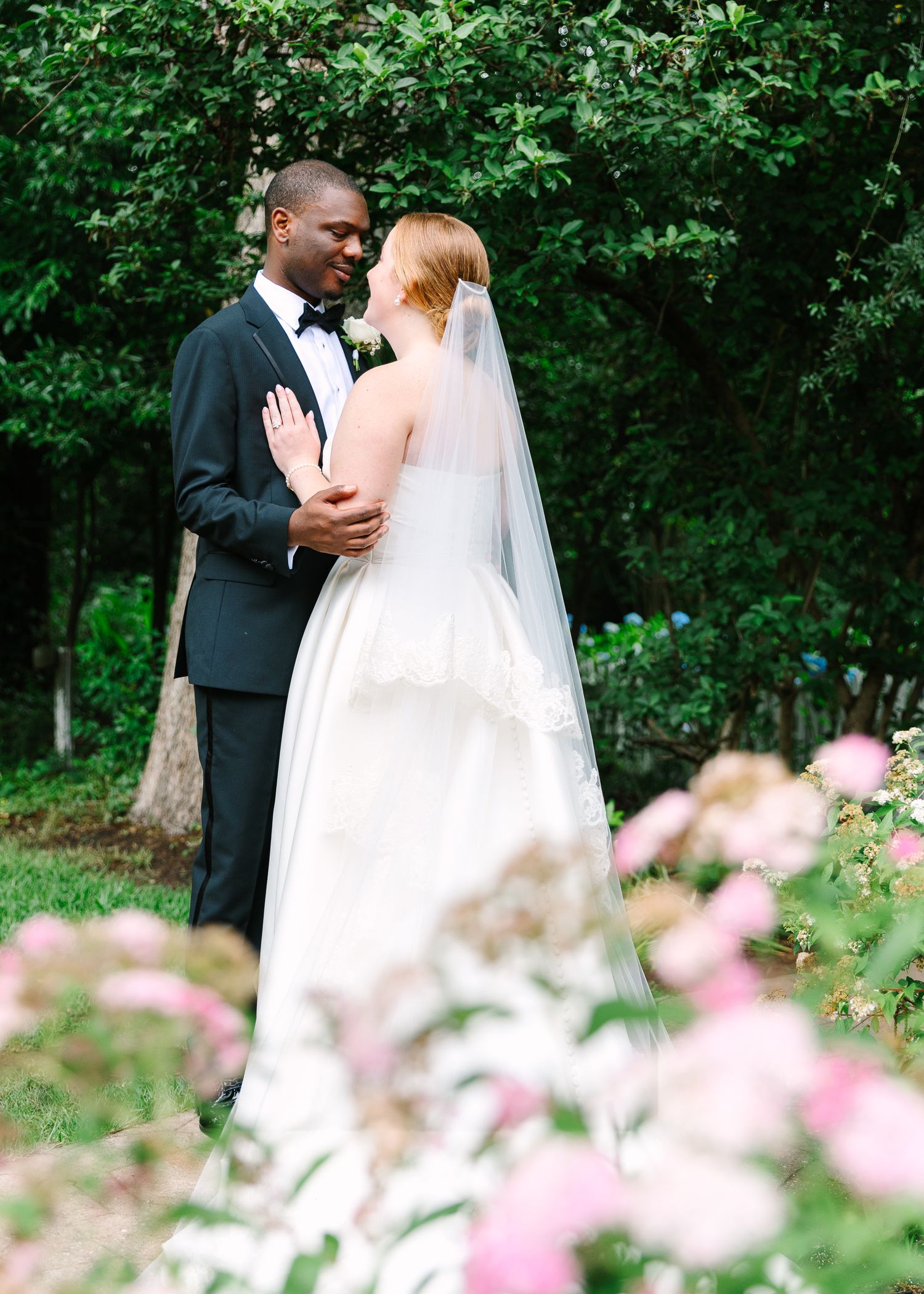 Romantic garden wedding portraits with pink flowers in the foreground.