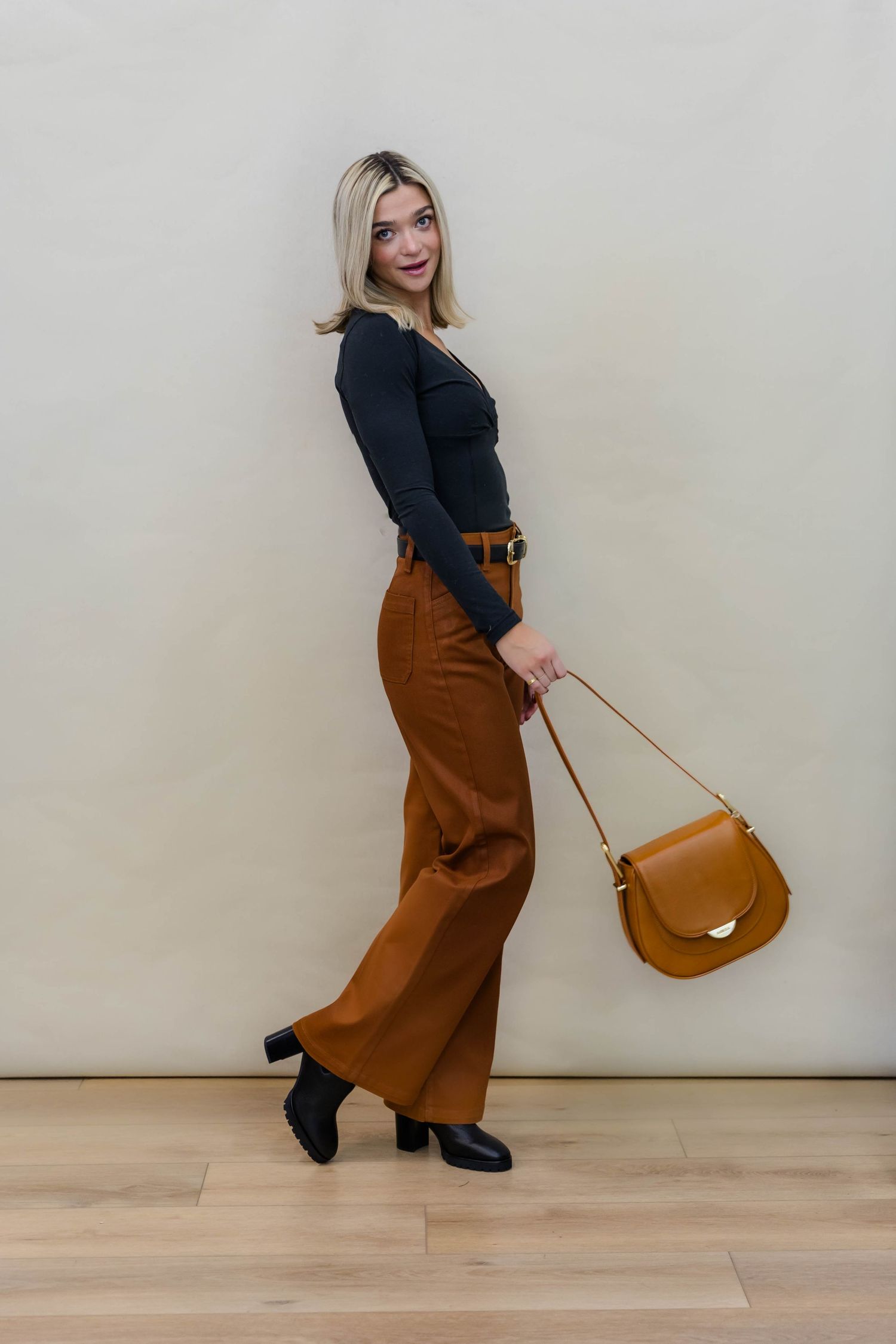 Black top paired with brown wide-leg pants and matching leather handbag for sophisticated style.