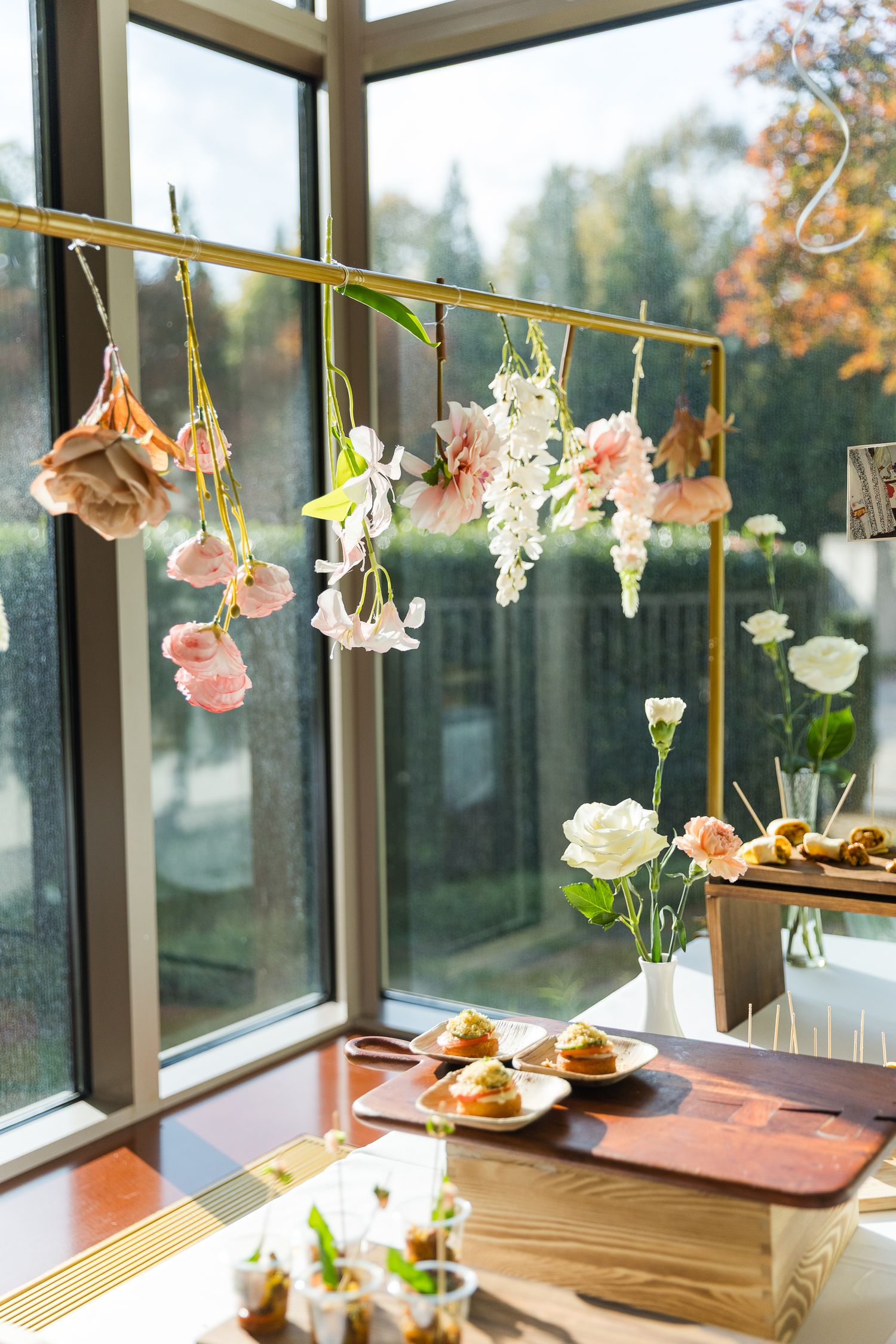 Delicate flowers hanging from strings create a romantic window display with sunlight streaming through.