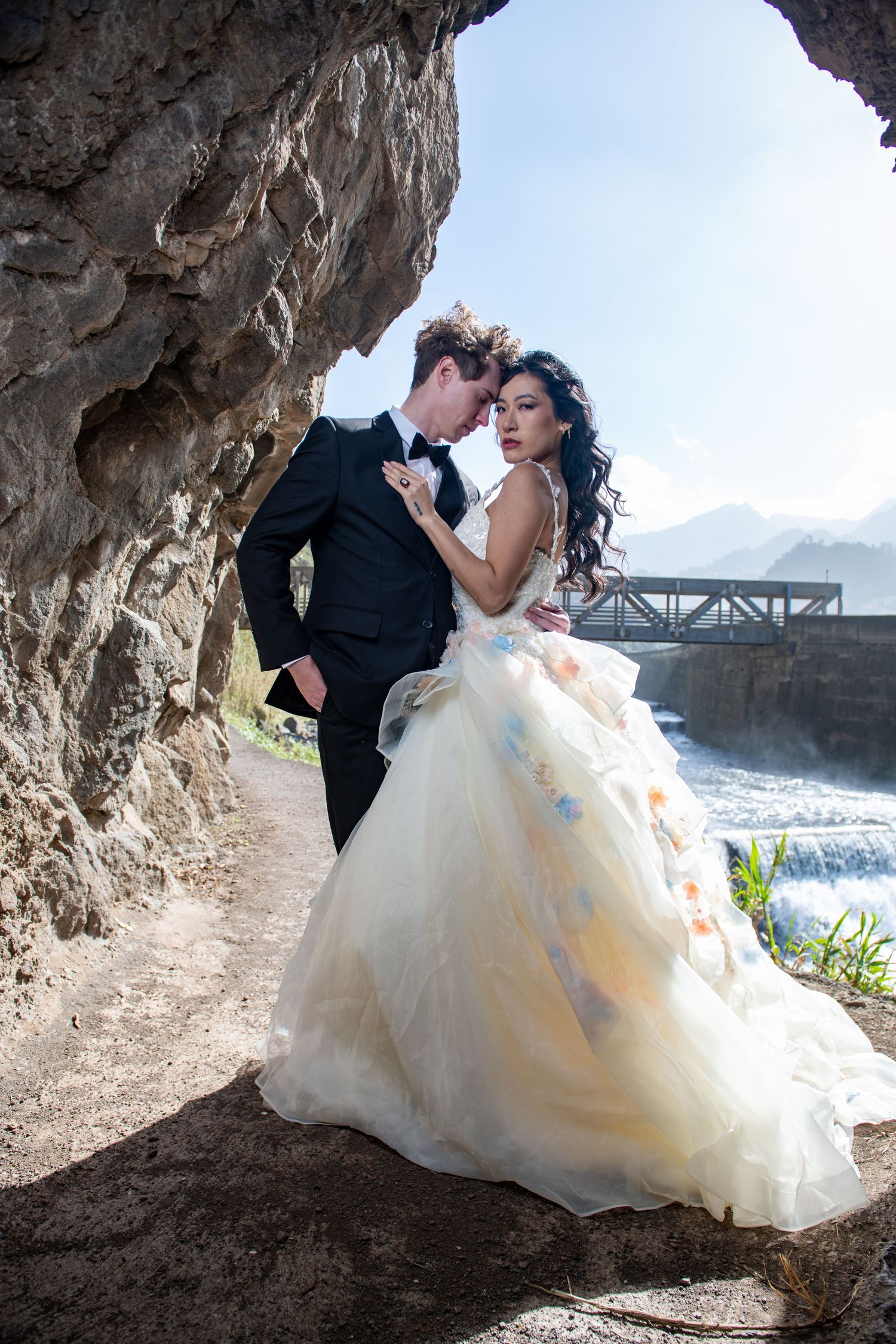 Romantic wedding photo shoot under a rocky cave formation by the ocean.