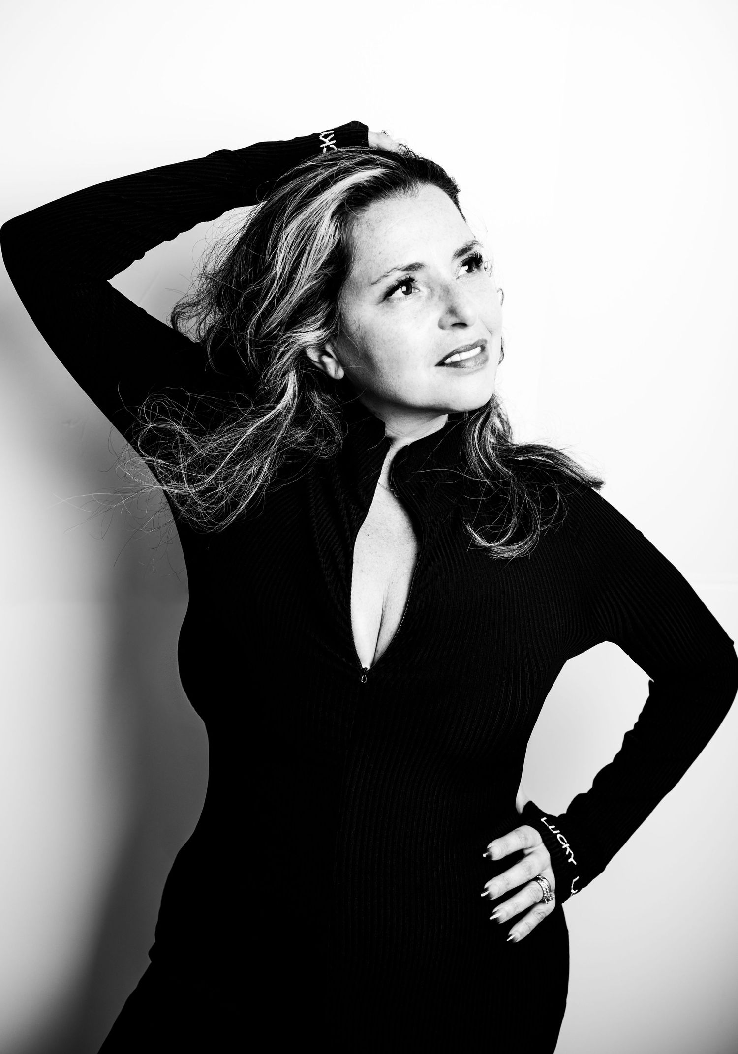 Dramatic black and white portrait with flowing hair and black top in artistic lighting.