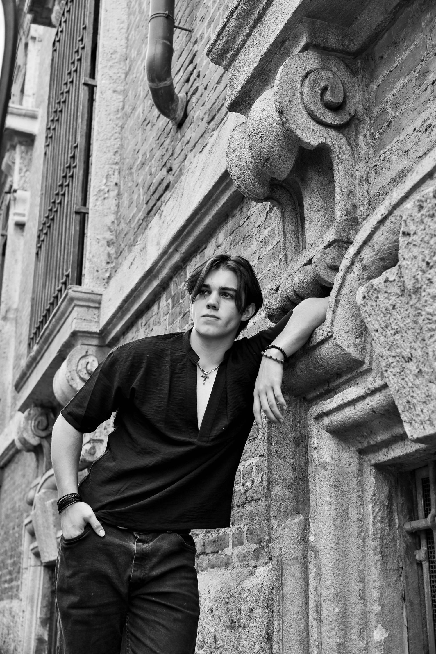Casual black outfit photographed in monochrome against stone architectural details.