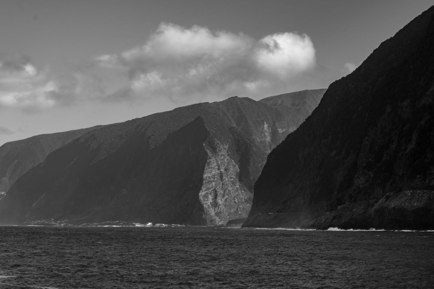 Panoramic black and white landscape of dramatic coastal cliffs and mountains.
