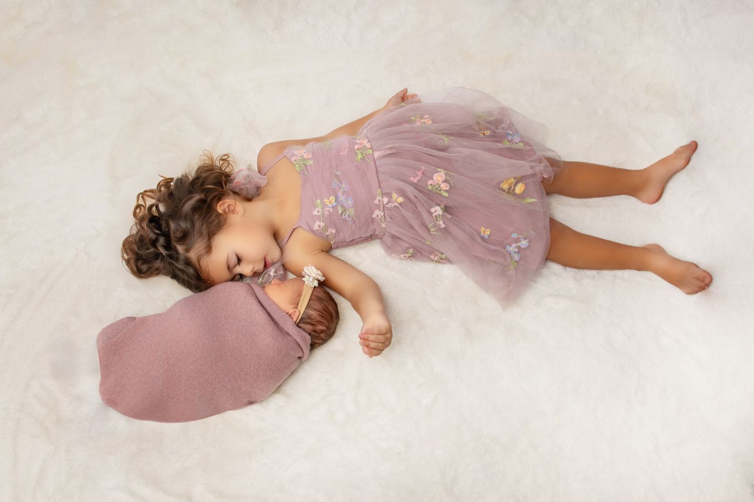 Series of artistic poses showing child in purple dress lying on white backdrop.