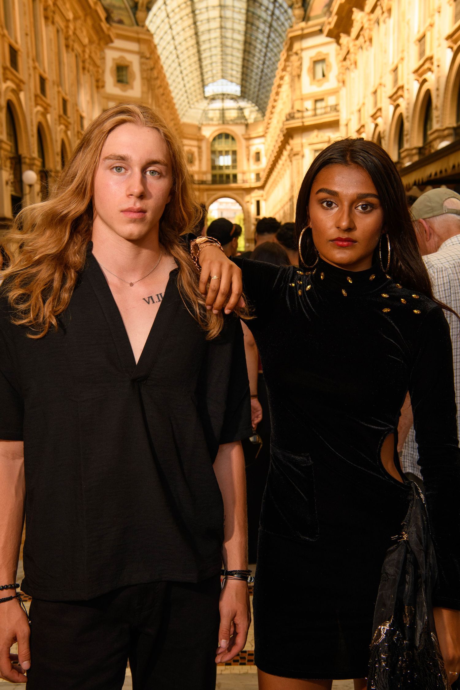 Models wearing black outfits walk through an ornate indoor gallery with vaulted glass ceiling.