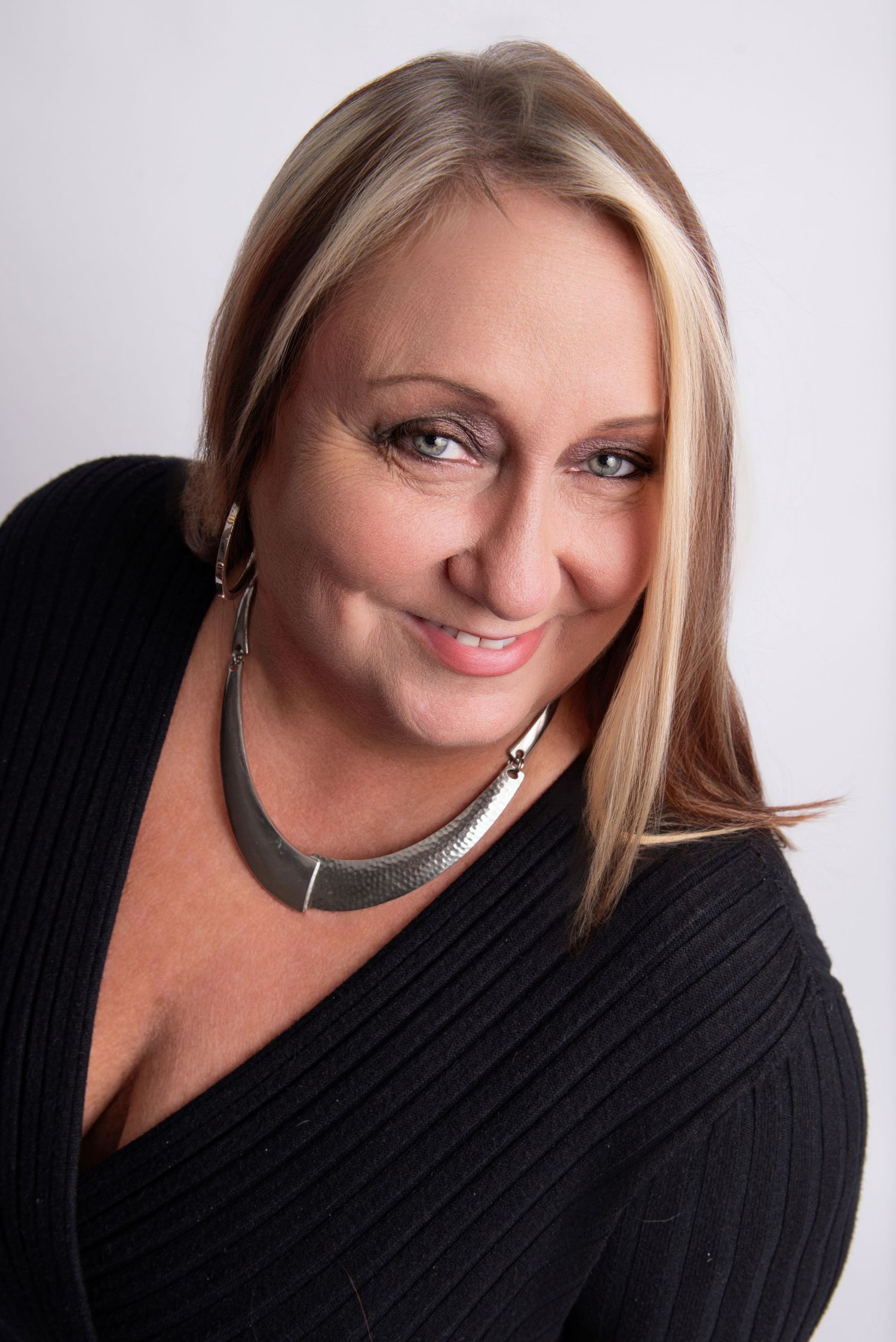 Studio portrait of a woman in black ribbed sweater with silver necklace.