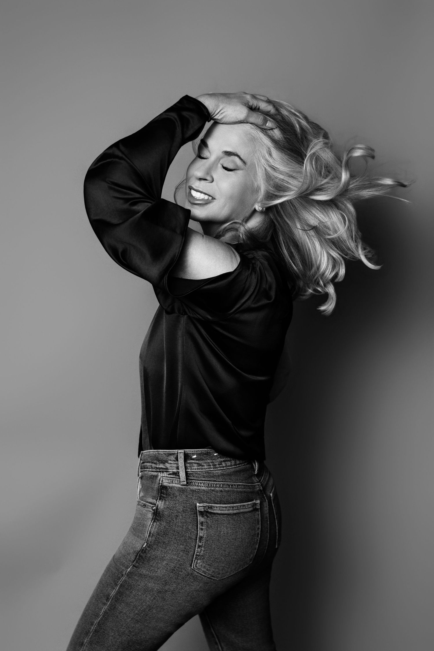Dynamic black and white photo of someone in jeans and black top with flowing hair.