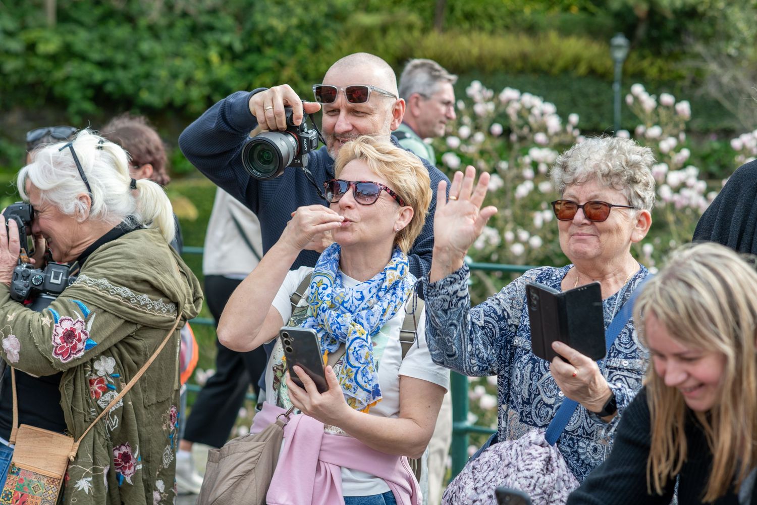 Group of people taking photos with cameras and phones at an outdoor event.