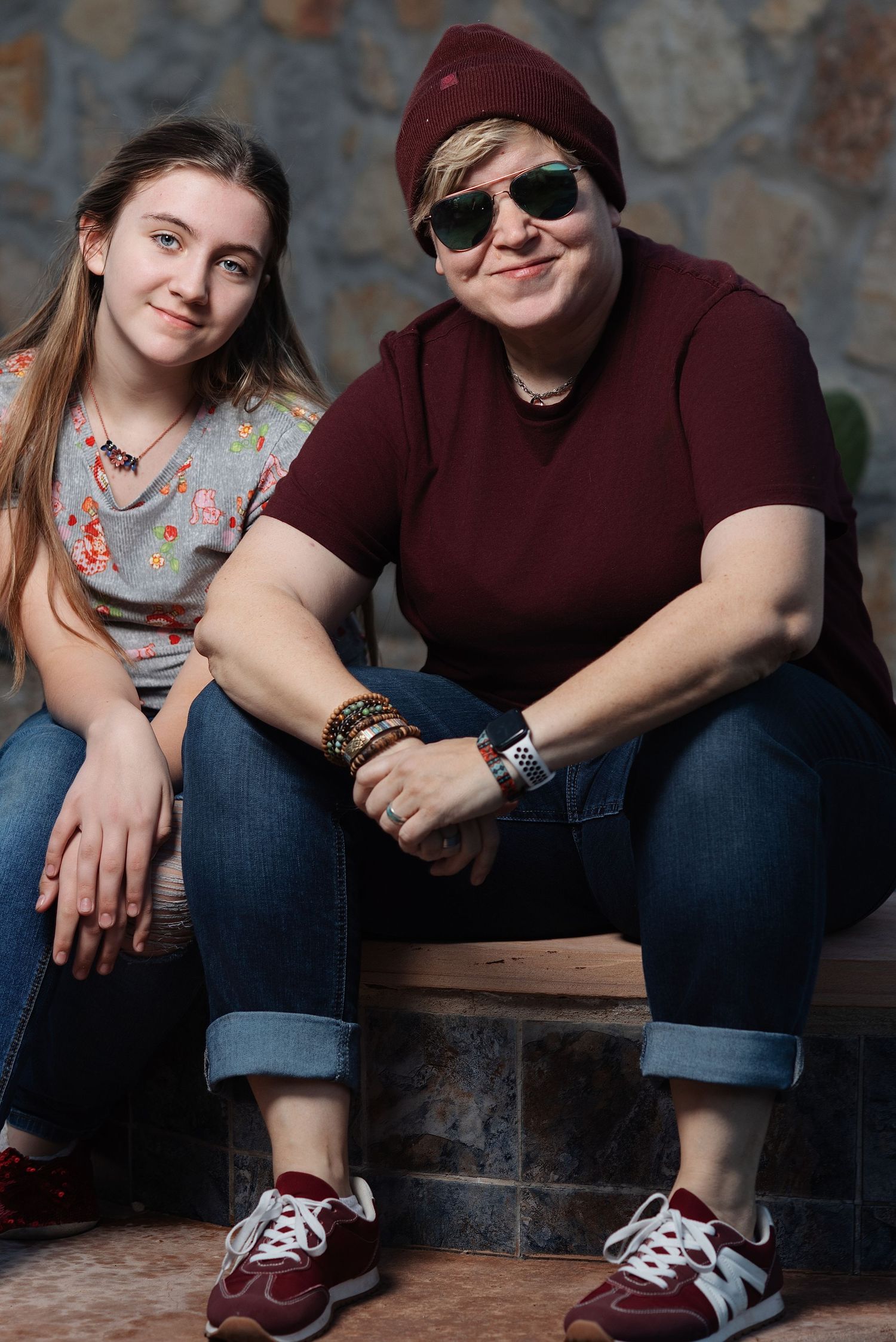 Two people in burgundy and denim sitting casually on stone steps.
