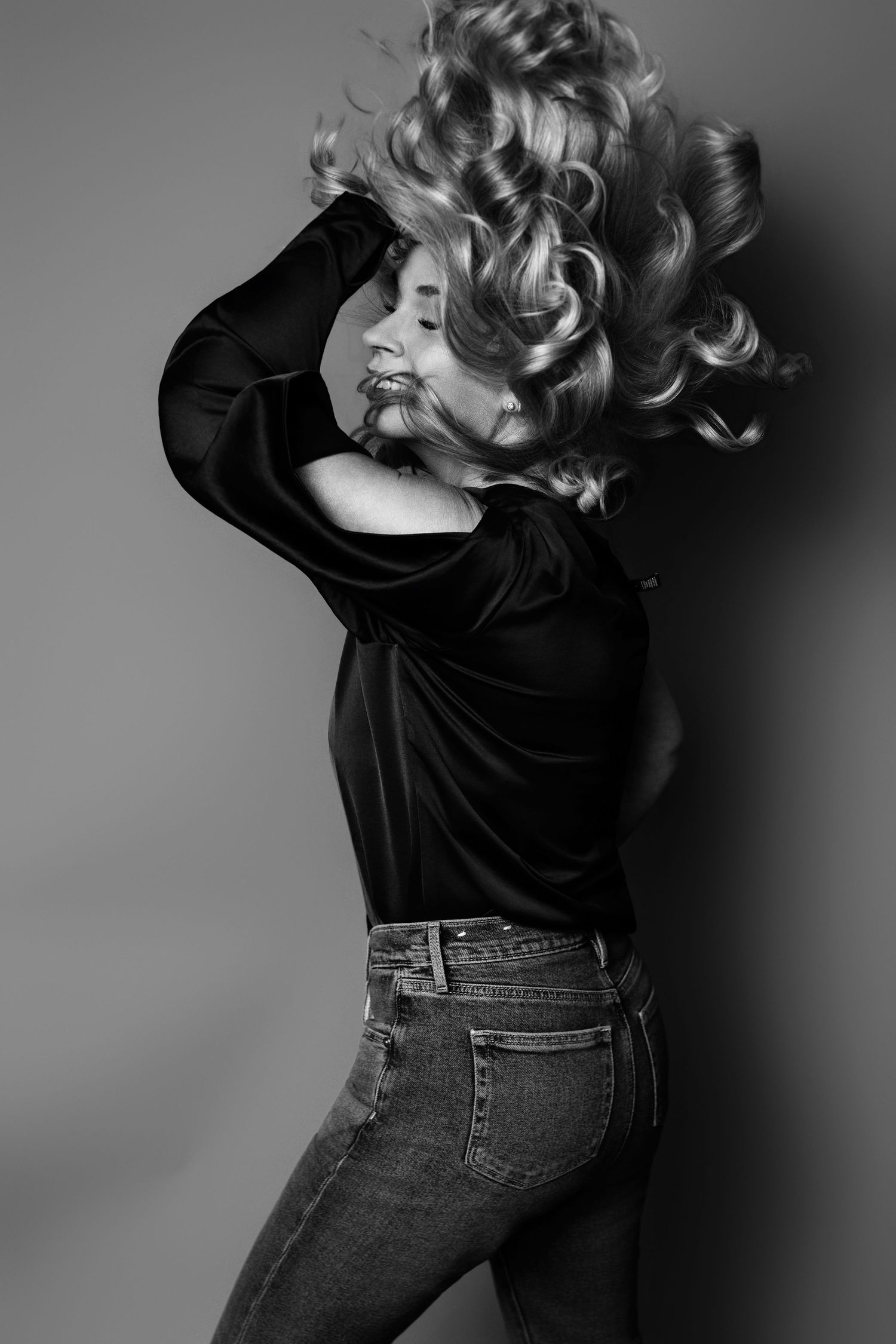 Artistic black and white photo capturing dynamic hair movement against grey background.