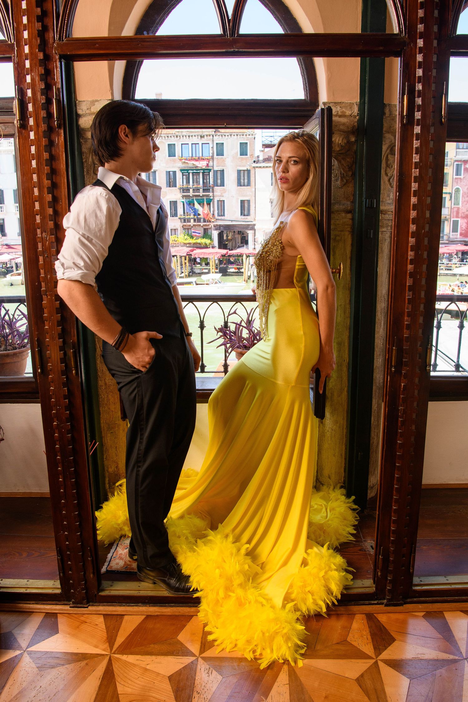 Formal couple posing in ornate Venetian interior with arched windows.