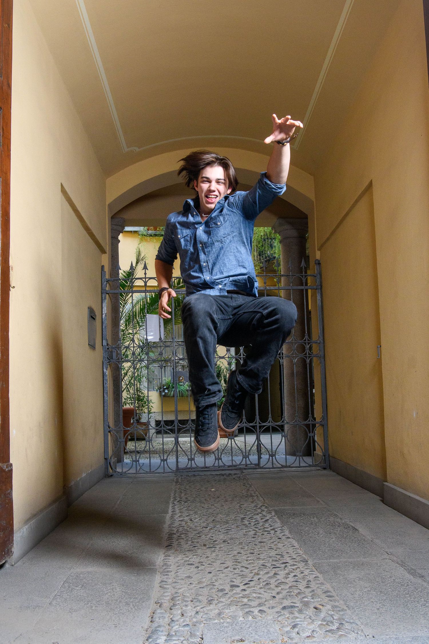Energetic jump shot captured in arched hallway with natural lighting.