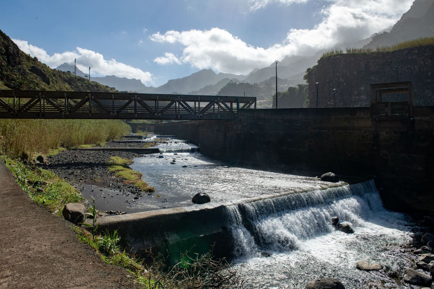 Series of waterfall views with bridge and mountain landscape in the background.