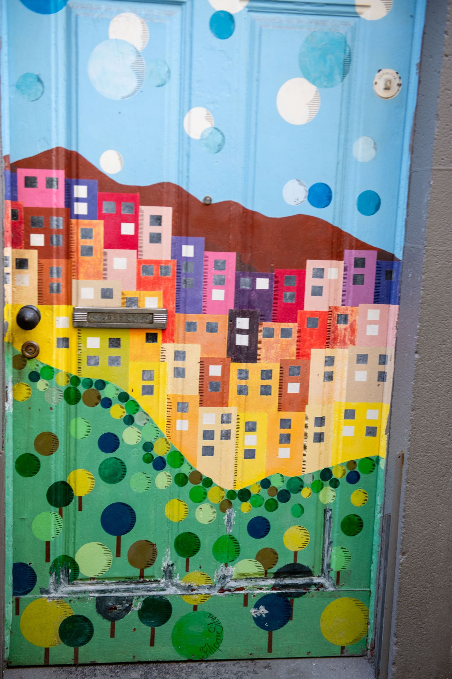 Vibrant mural depicting colorful cityscape with buildings and trees in bubble-like geometric style.