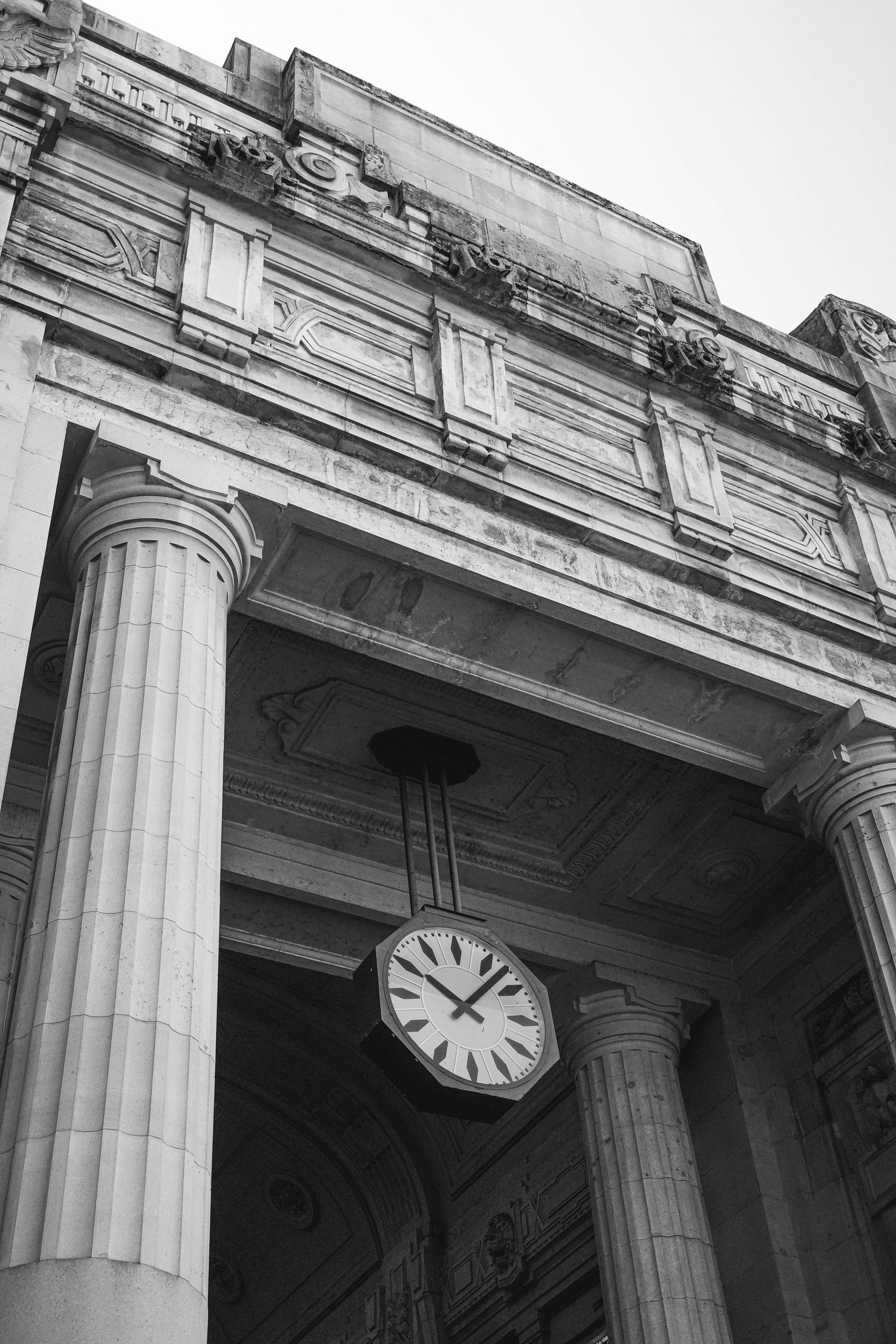 Black and white architectural detail of a classical building entrance with columns and clock.