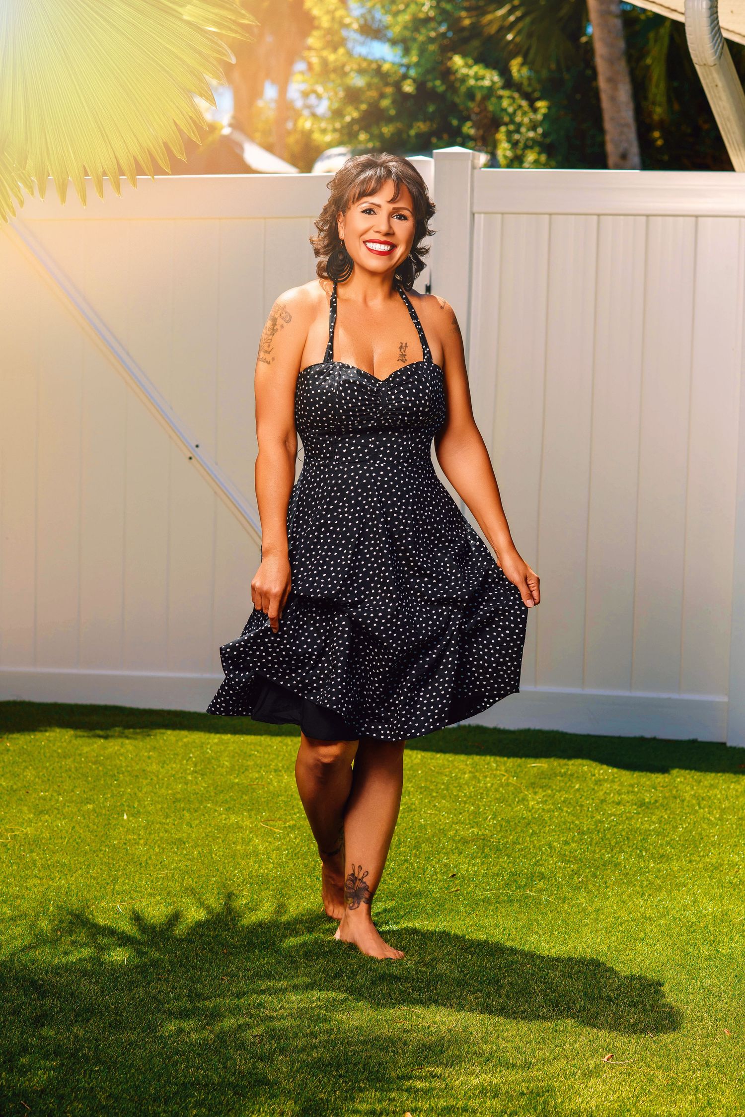 Energetic outdoor photos in polka dot dress showing playful movements on grass.