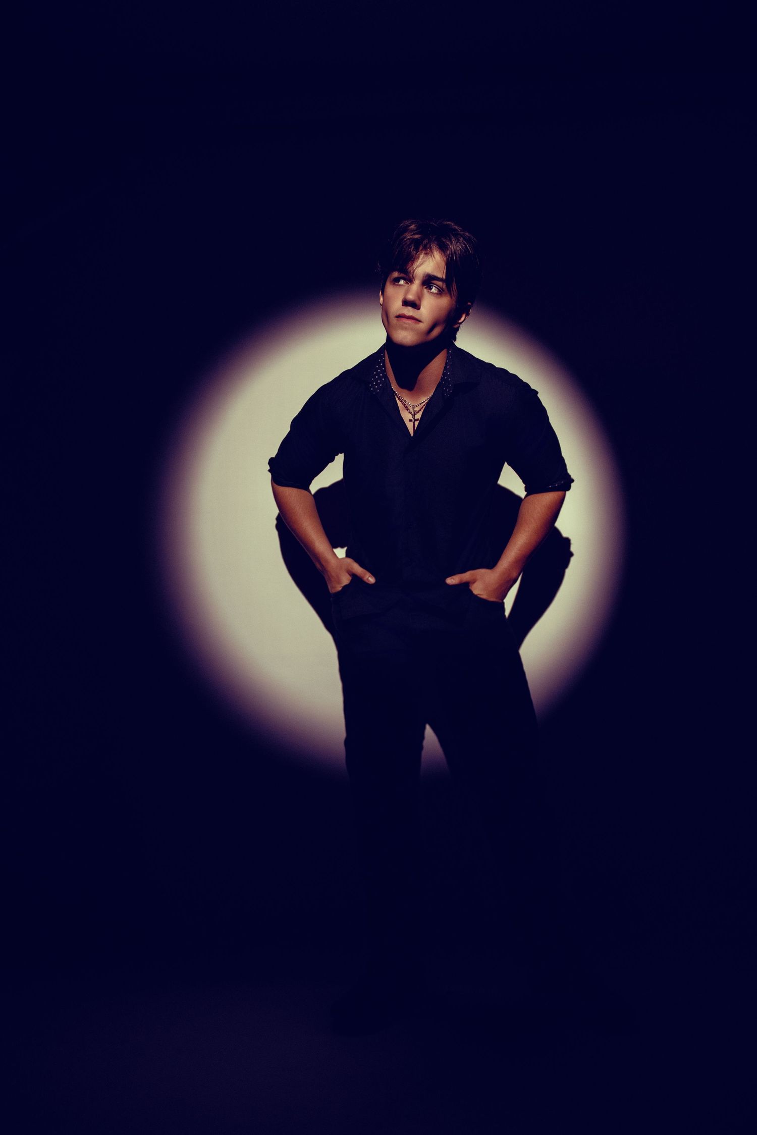 Artistic silhouette photo of person in dark clothing against circular light backdrop.