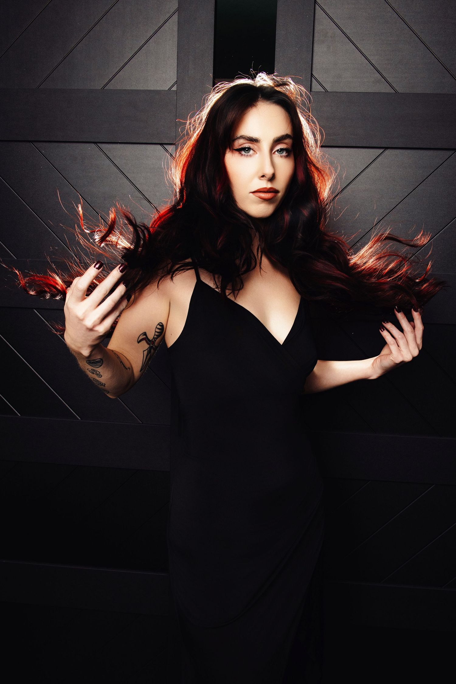Dramatic portrait against dark background with flowing hair and moody lighting.