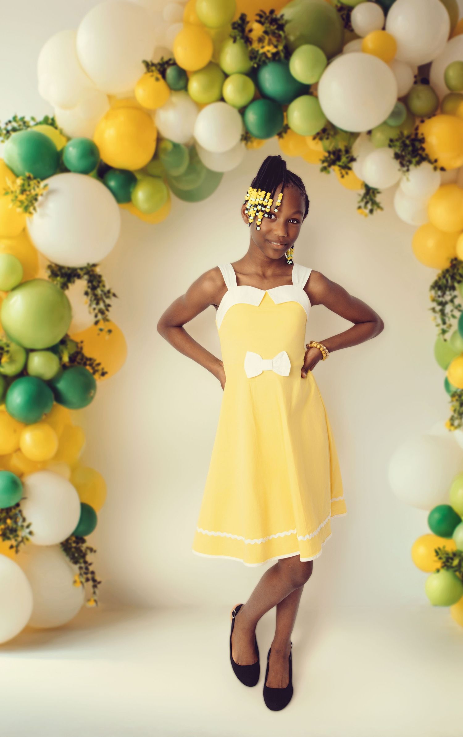 A yellow dress photoshoot with balloon arch decorations in green, yellow and white.