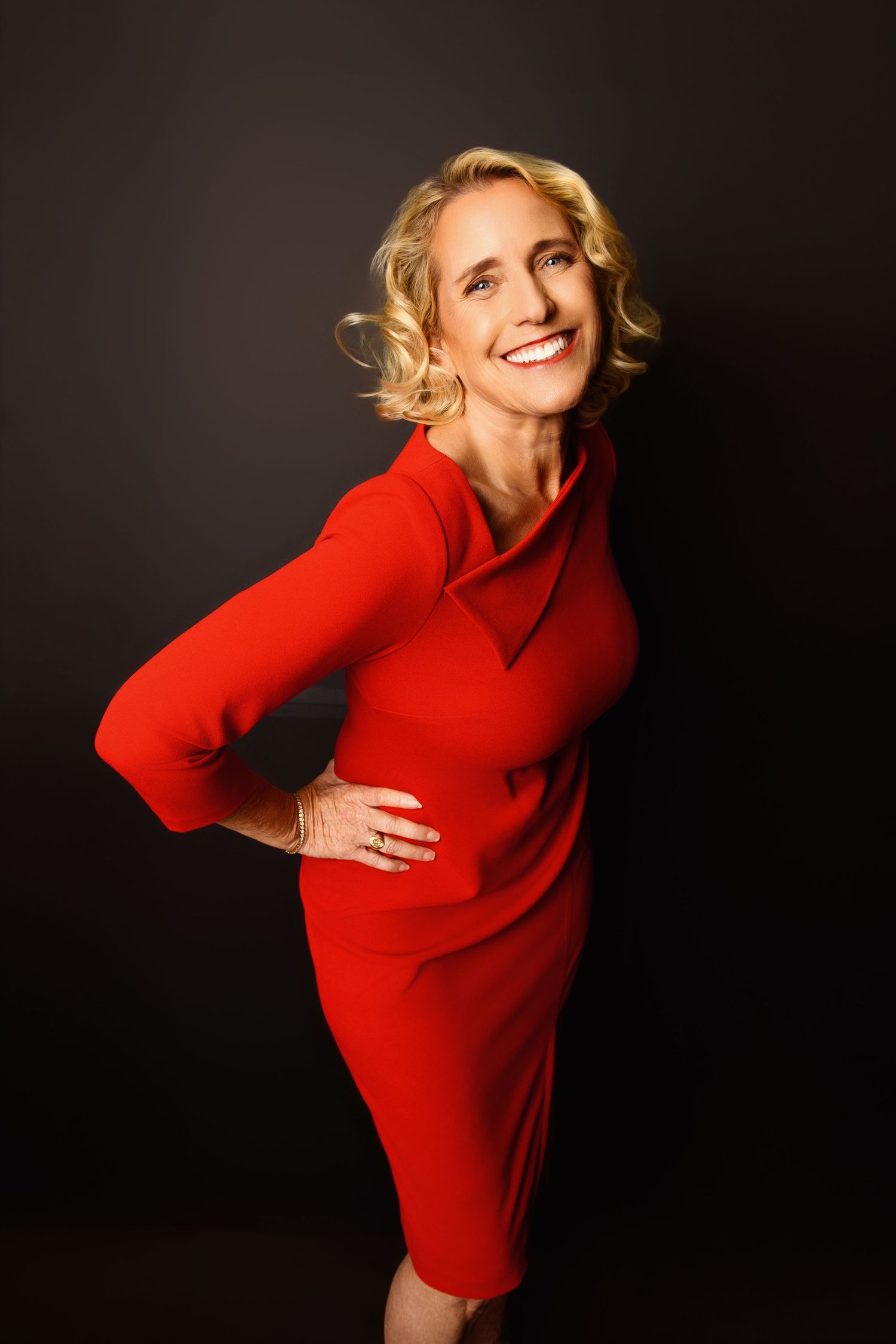 Dynamic fashion poses in a vibrant red dress against black backdrop.