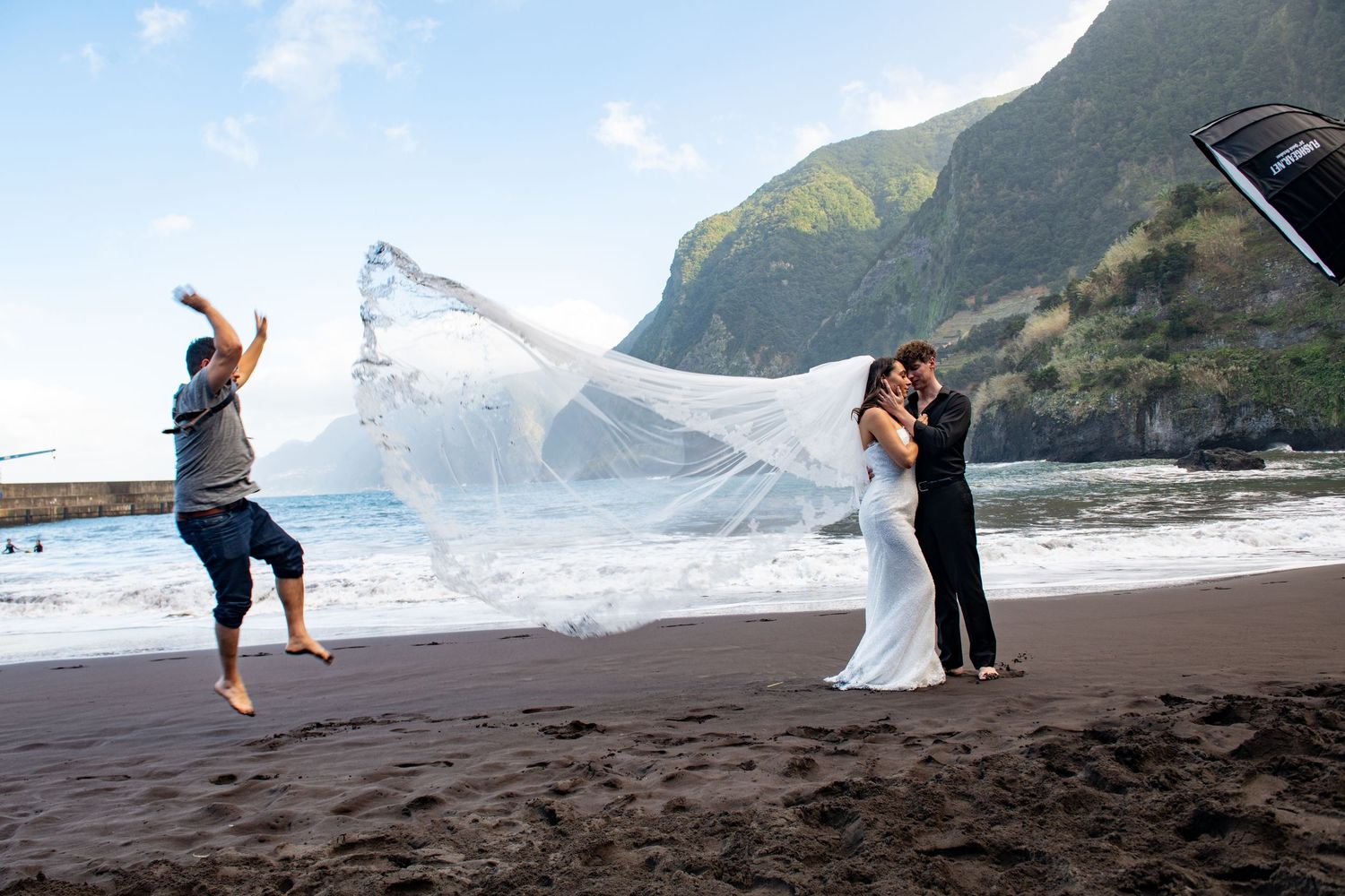 Wedding photo series on a volcanic beach with towering cliffs in the background.
